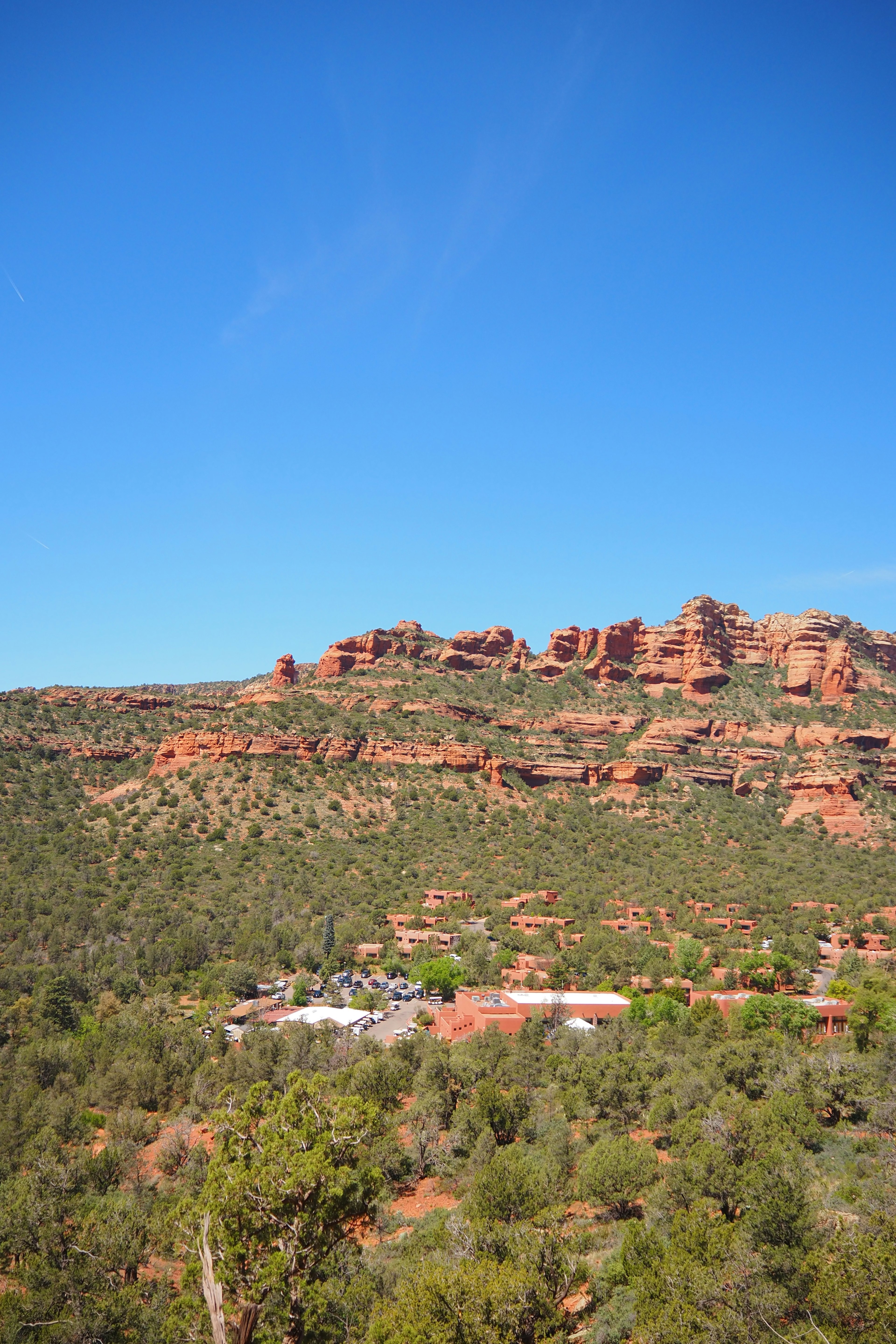 Vue panoramique des formations rocheuses rouges et de la végétation verte sous un ciel bleu clair