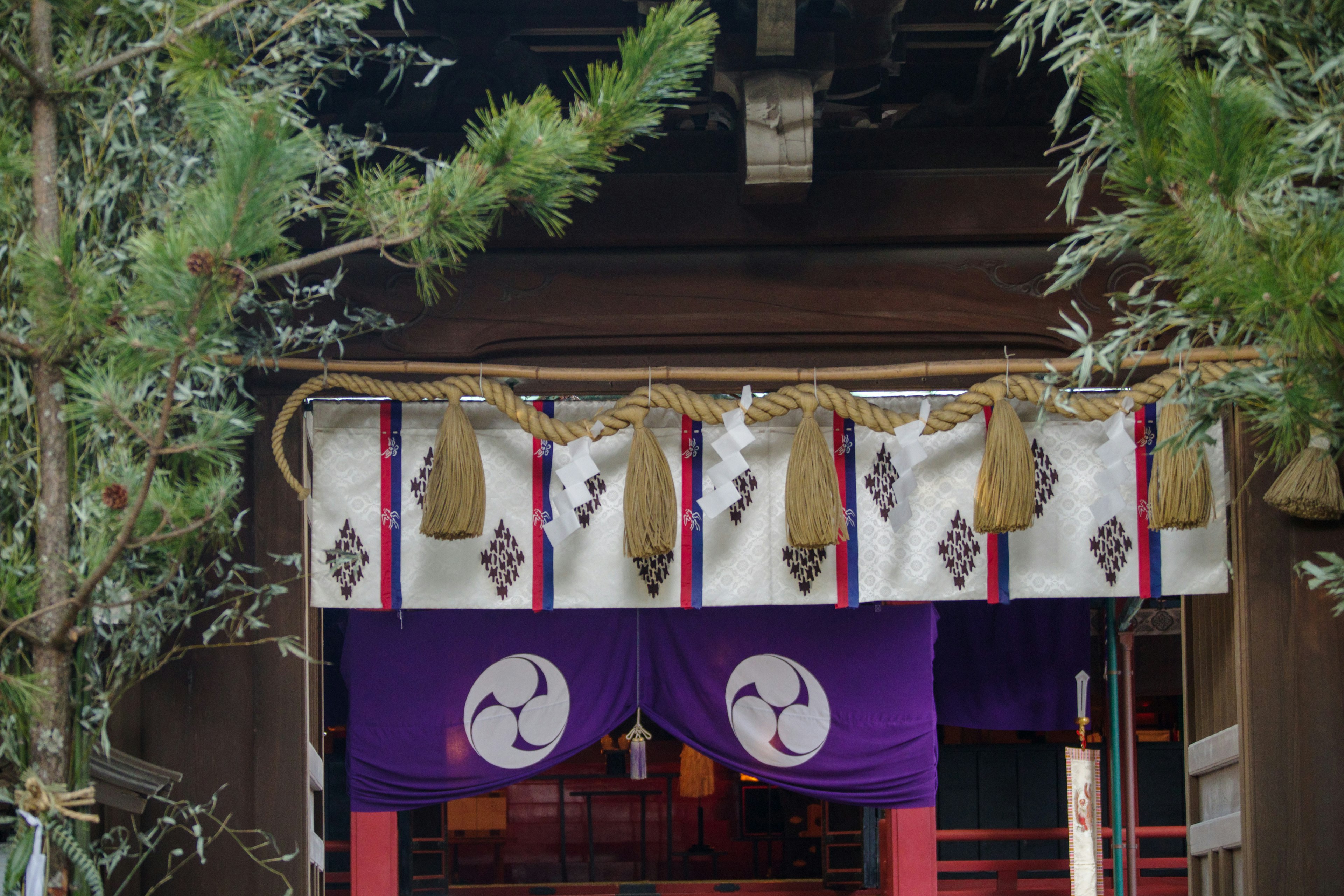 Entrance of a shrine adorned with purple curtains and traditional decorations