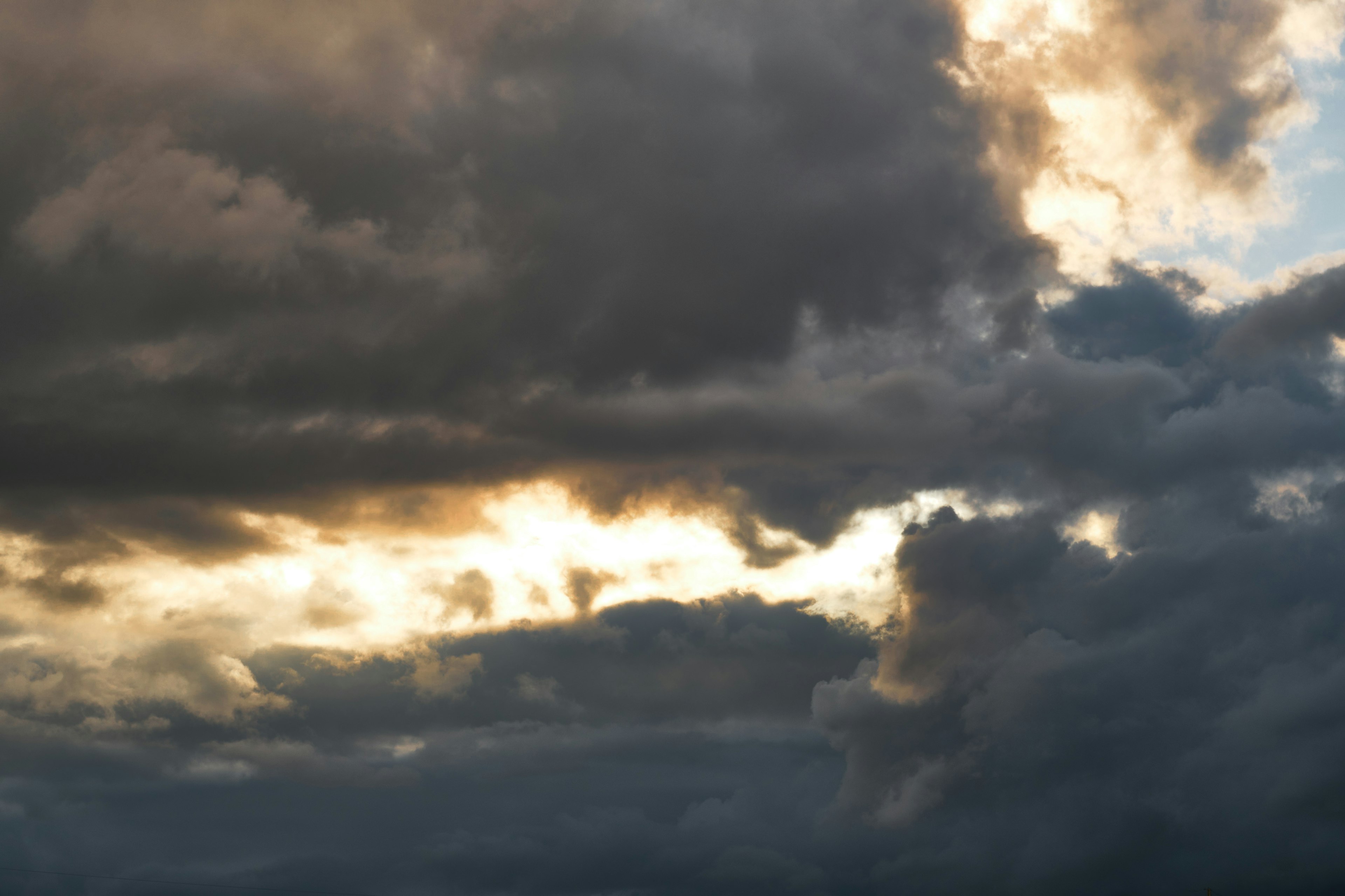 Cielo lleno de nubes oscuras y luz dorada brillando