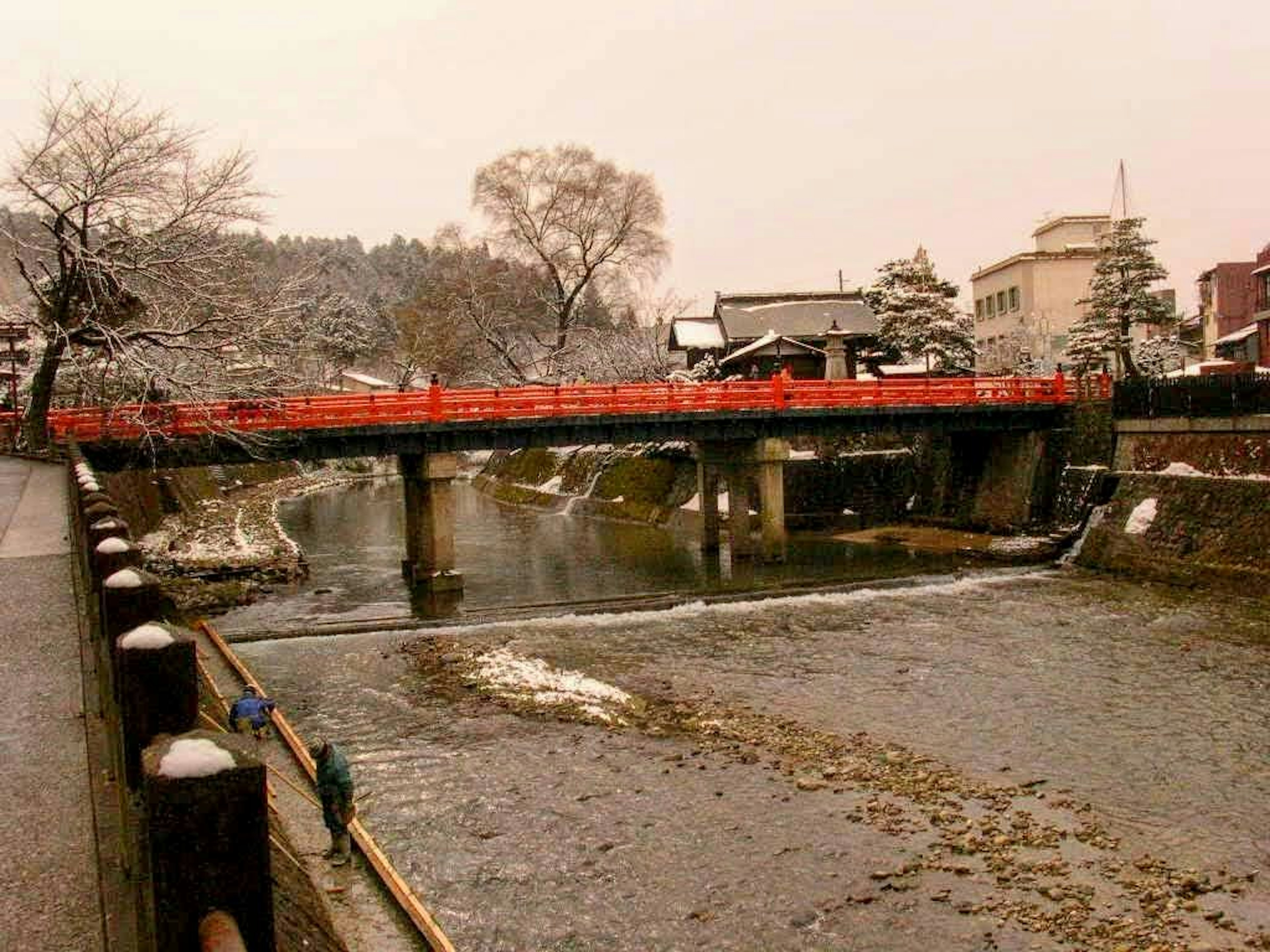 Río cubierto de nieve con un puente rojo en invierno