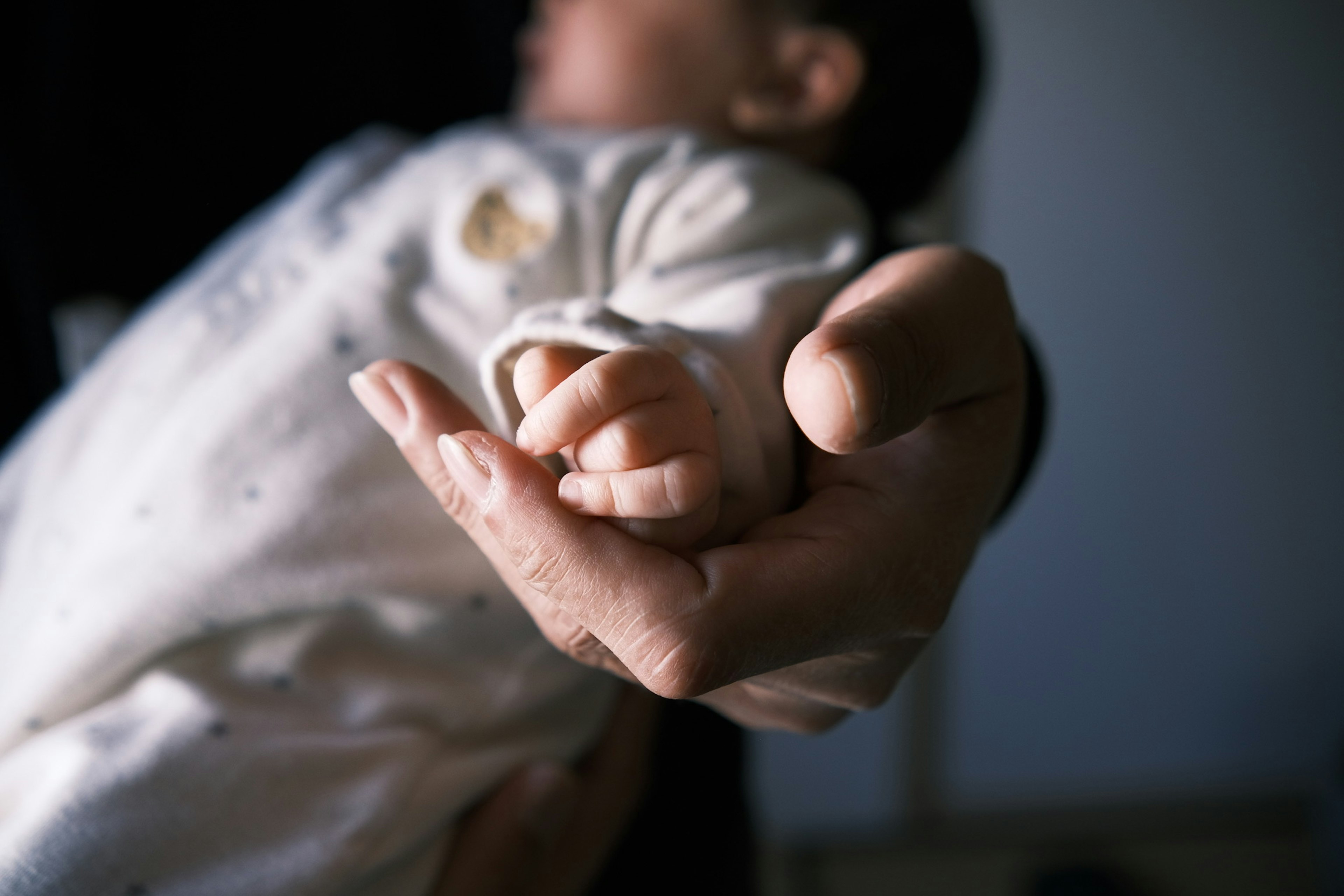 Nahaufnahme eines Babys, das die Hand eines Erwachsenen hält