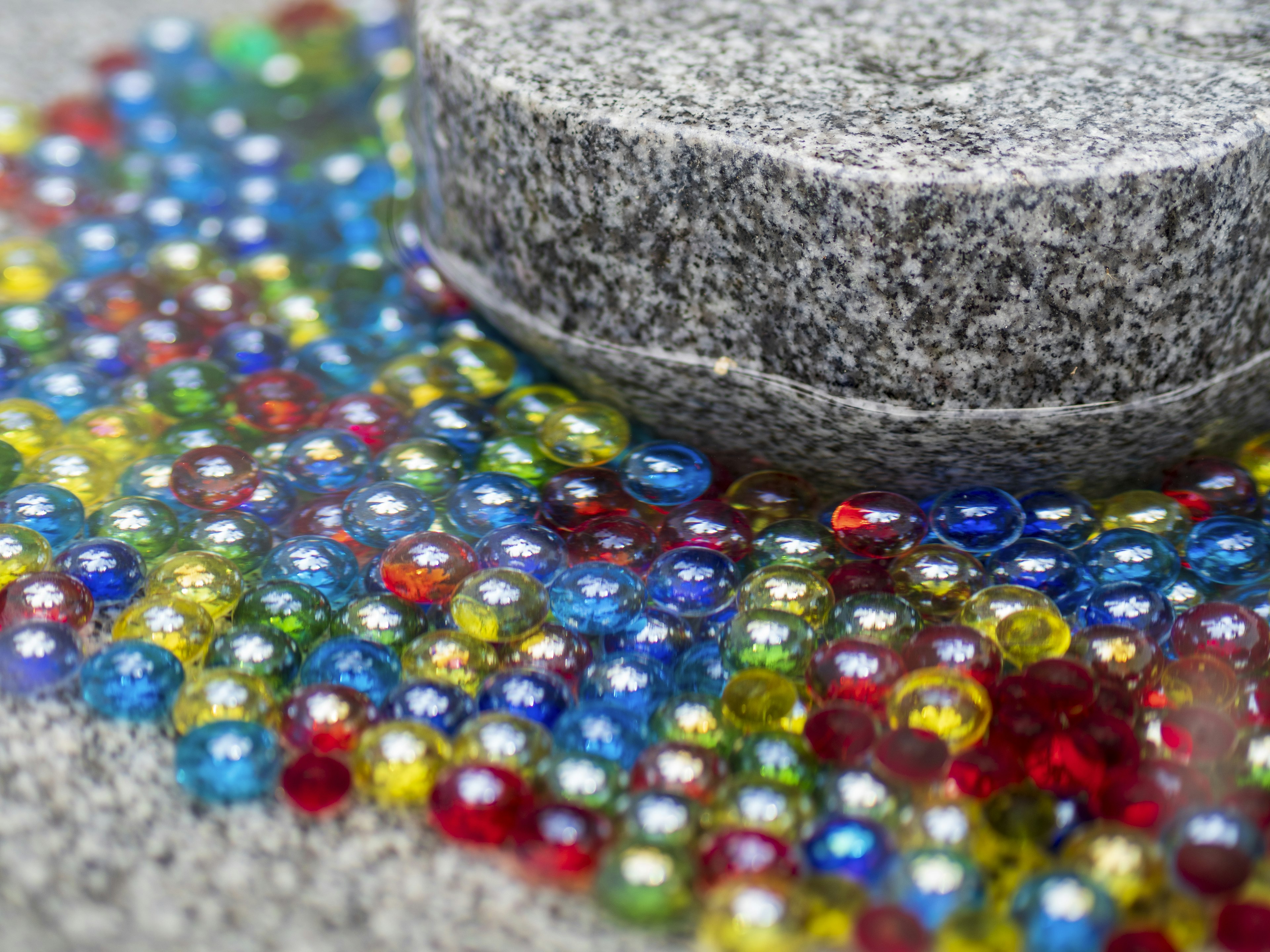 Colorful glass marbles scattered on a stone surface