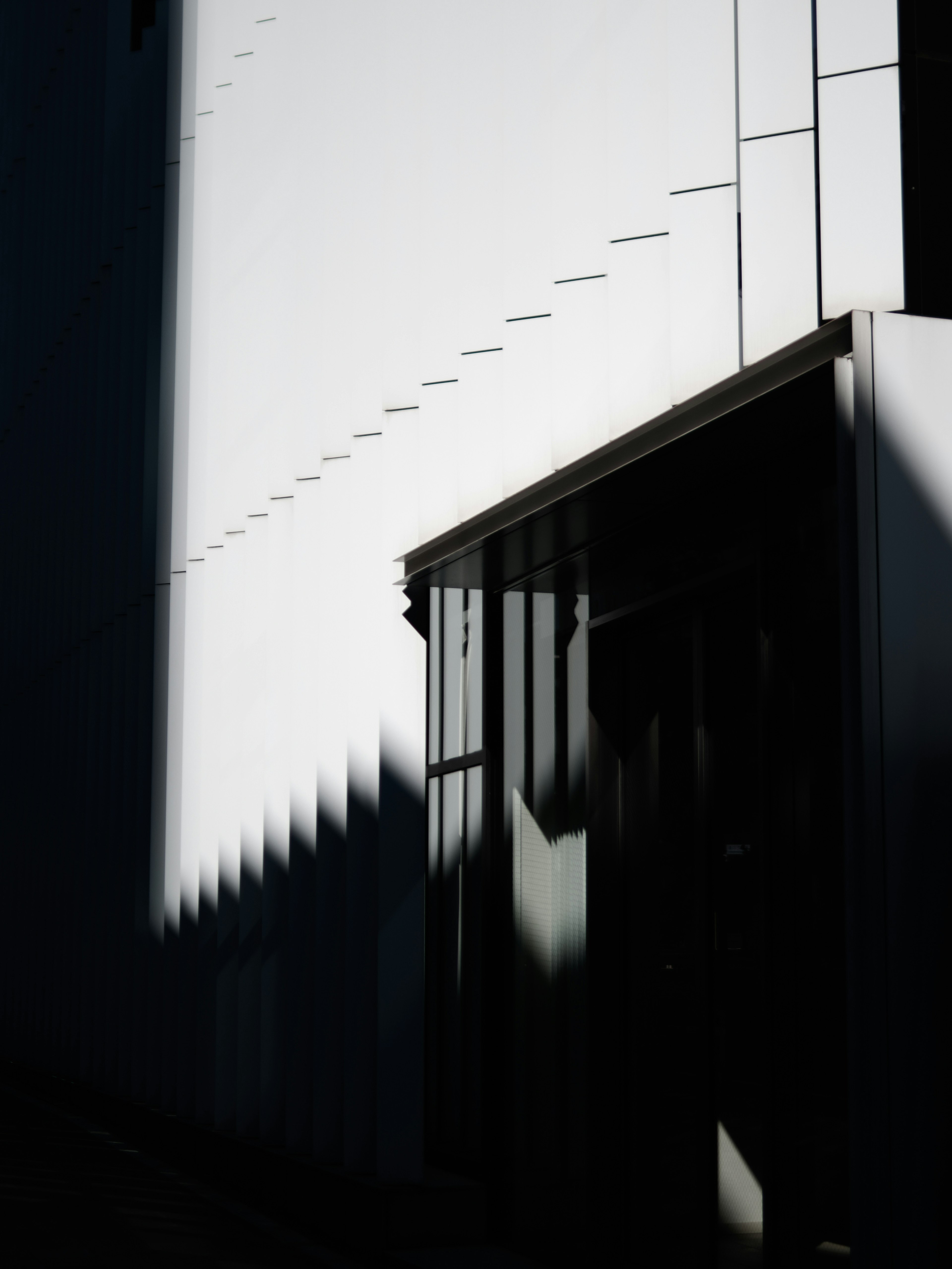 Un fuerte contraste entre la pared blanca y la sombra de un edificio