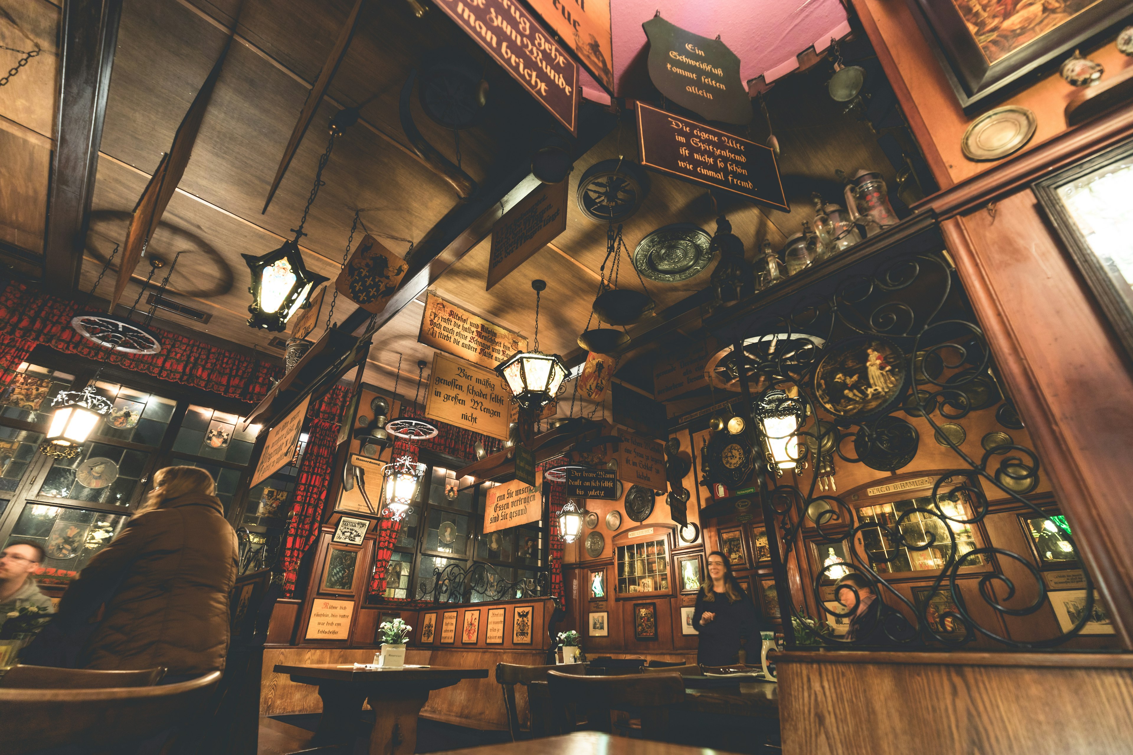 Interior of a historic pub with wooden furniture and decorative lamps featuring old signs and art on the walls