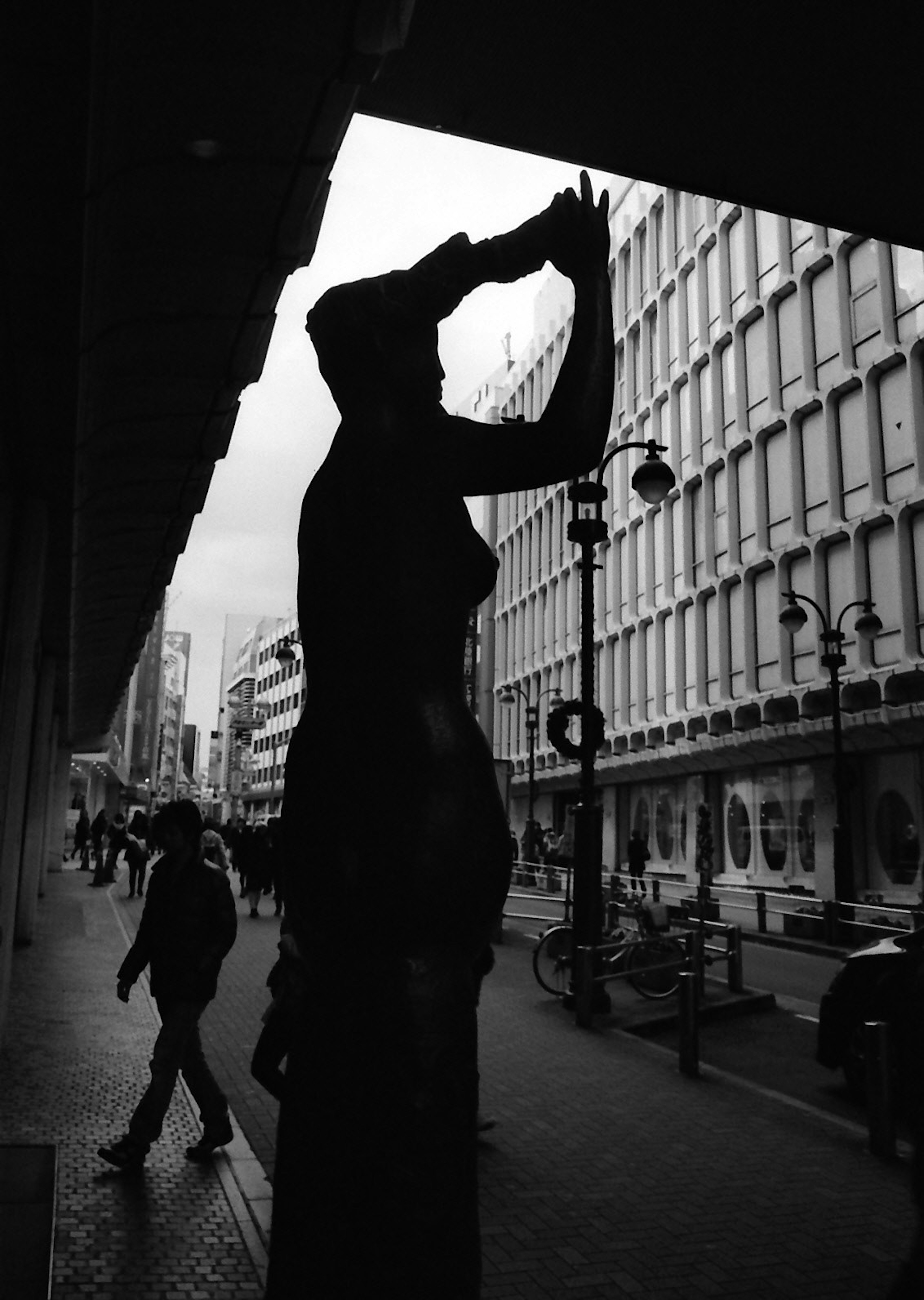 Silueta de una estatua posando en una calle de la ciudad con peatones