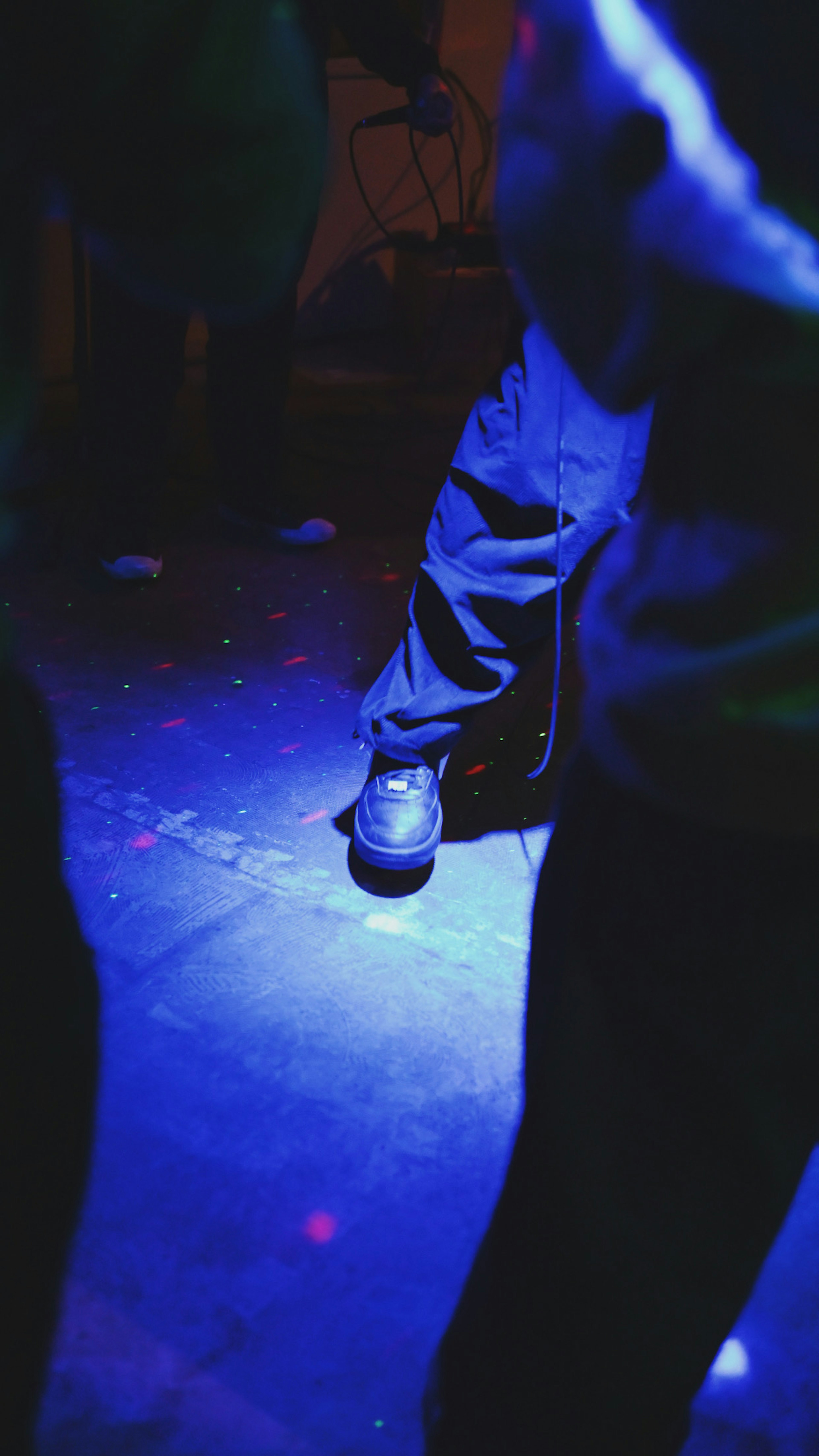 Pie con zapatos iluminado por luces azules en un suelo de club