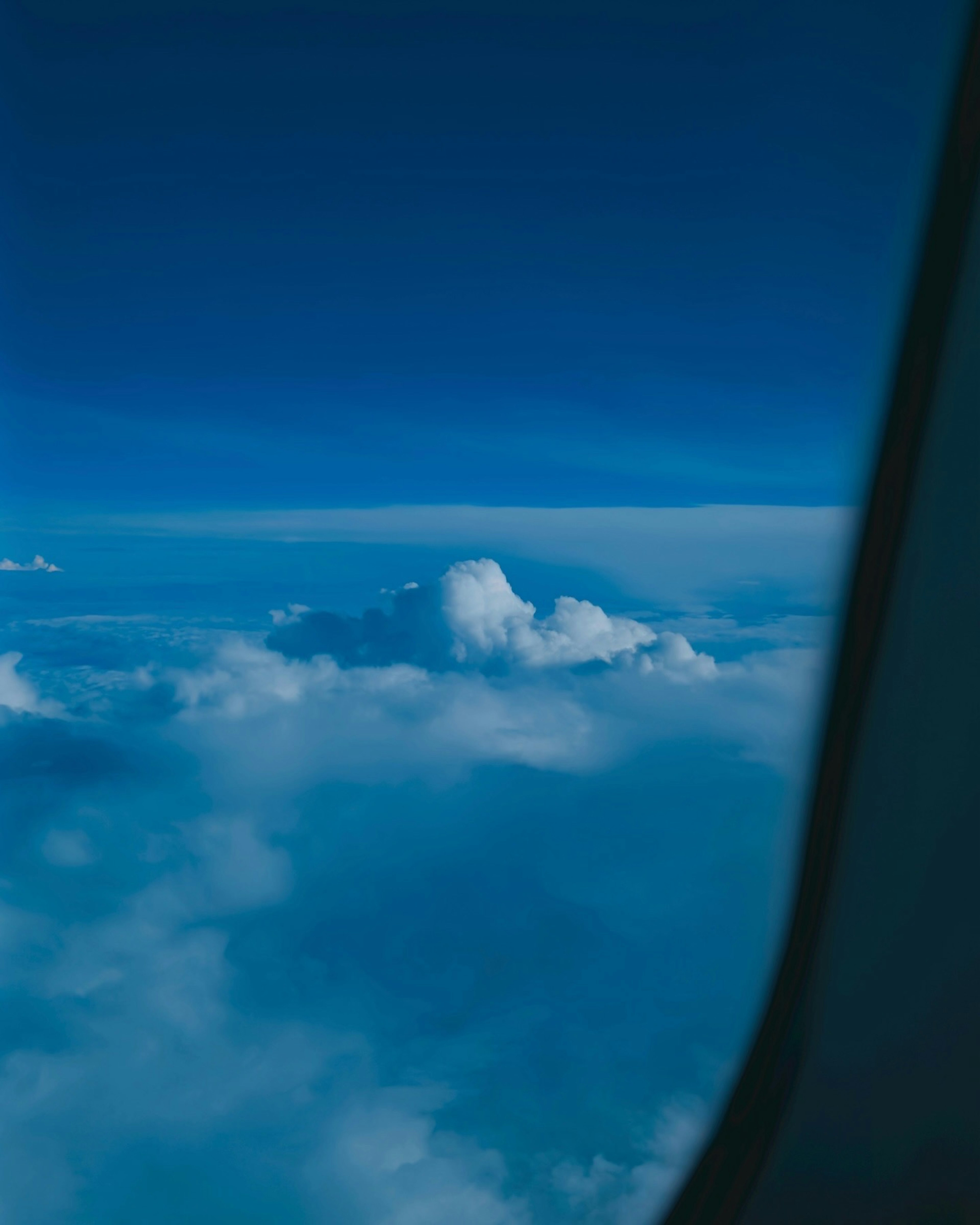 青い空と雲が広がる風景 窓の一部が見える