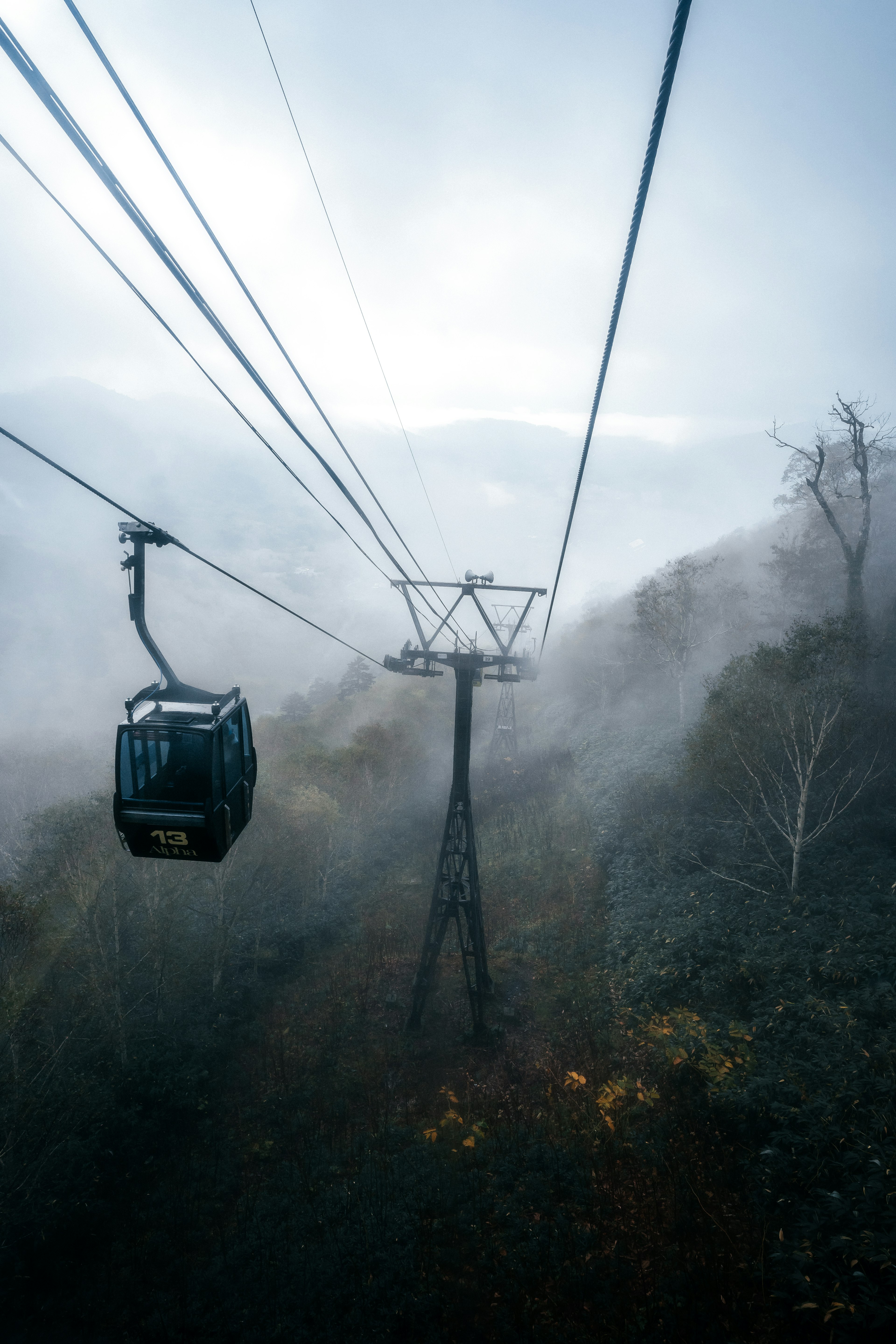 Eine Gondel, die durch den Nebel fährt, mit sichtbaren Kabeln