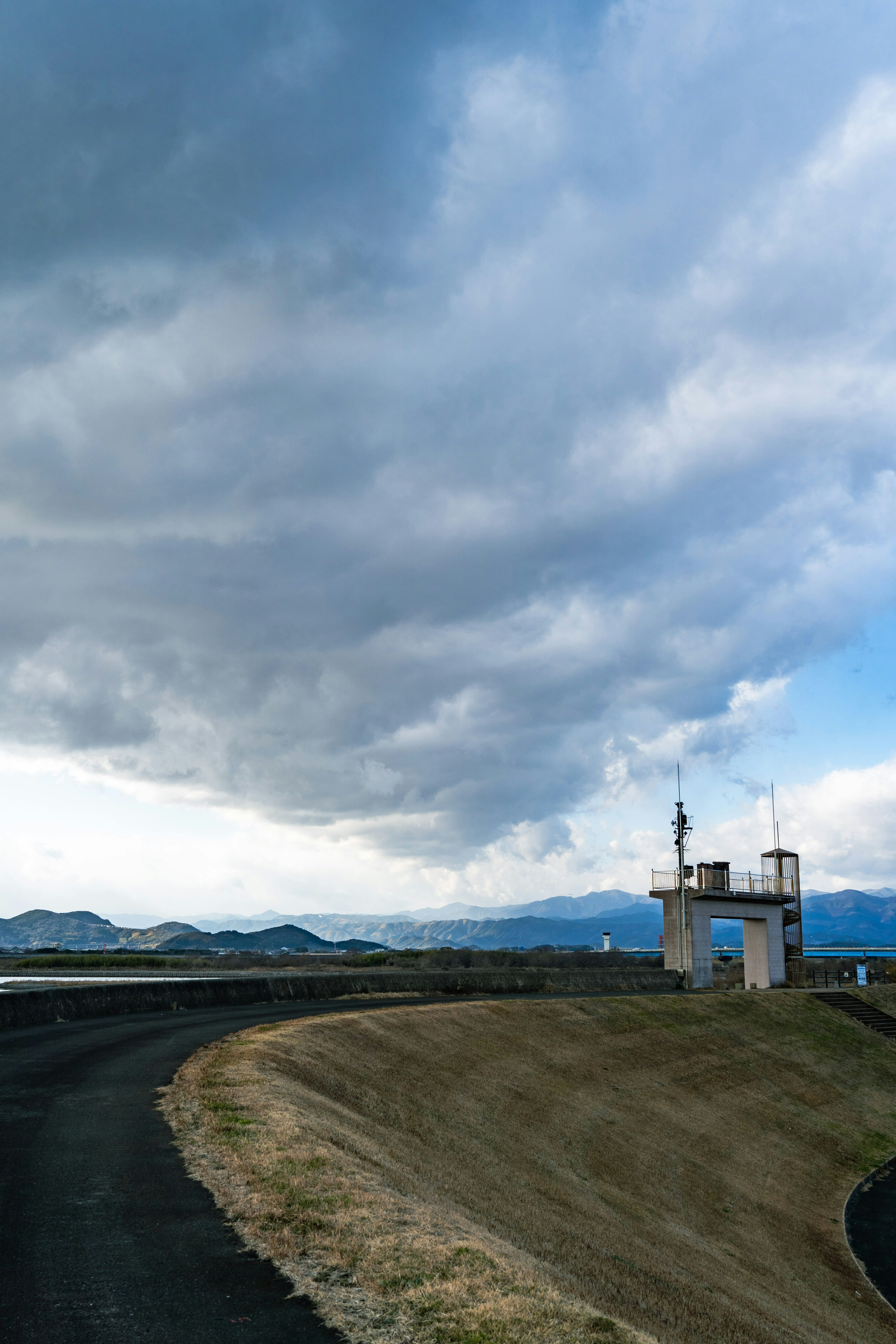 曲がりくねった道路と雲の多い空の景色に立つ監視塔