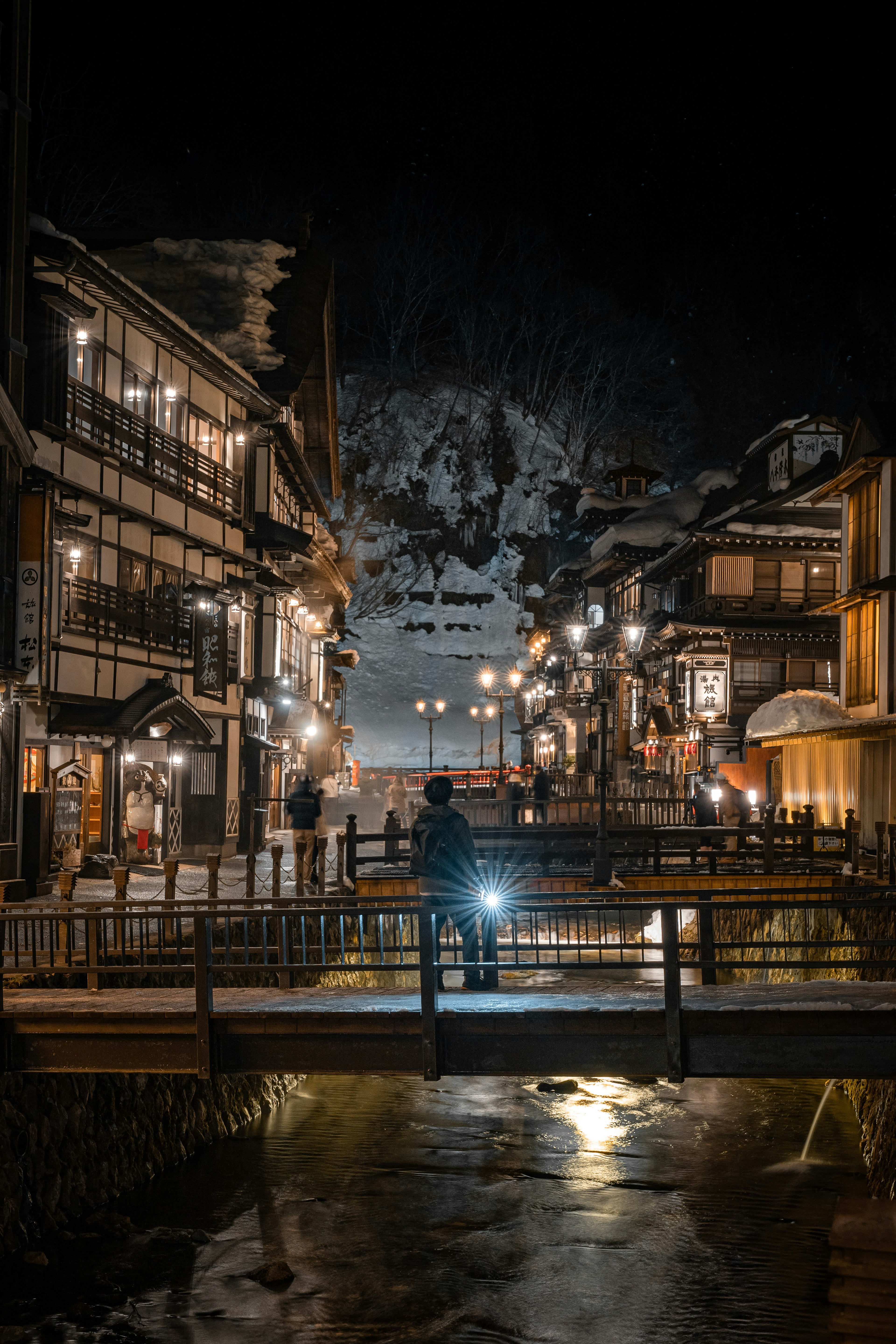 夜の温泉街の風景 小道と橋に照明が灯る