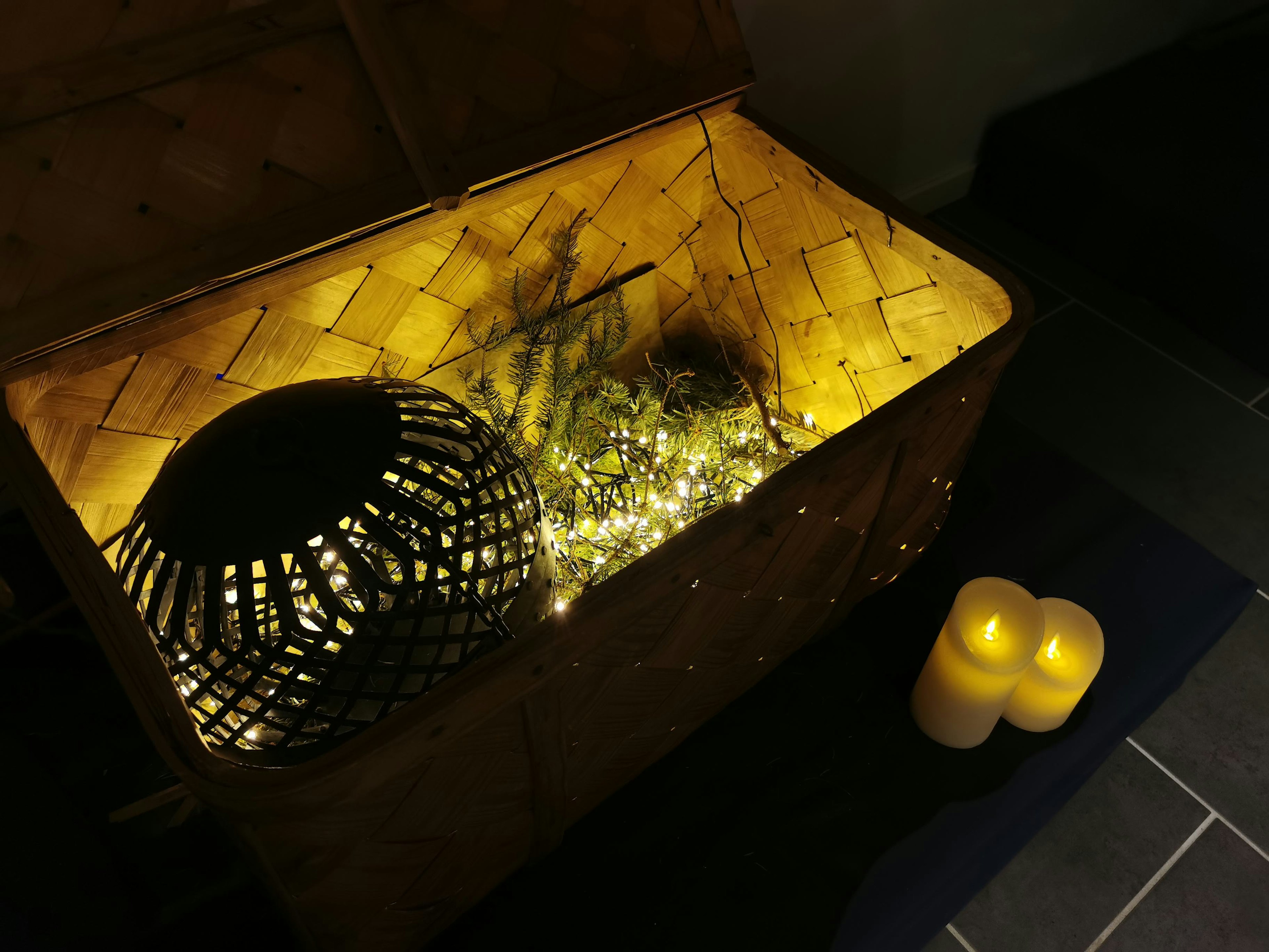 Un coin confortable avec un panier tissé illuminé par une lumière chaude et un ensemble de bougies