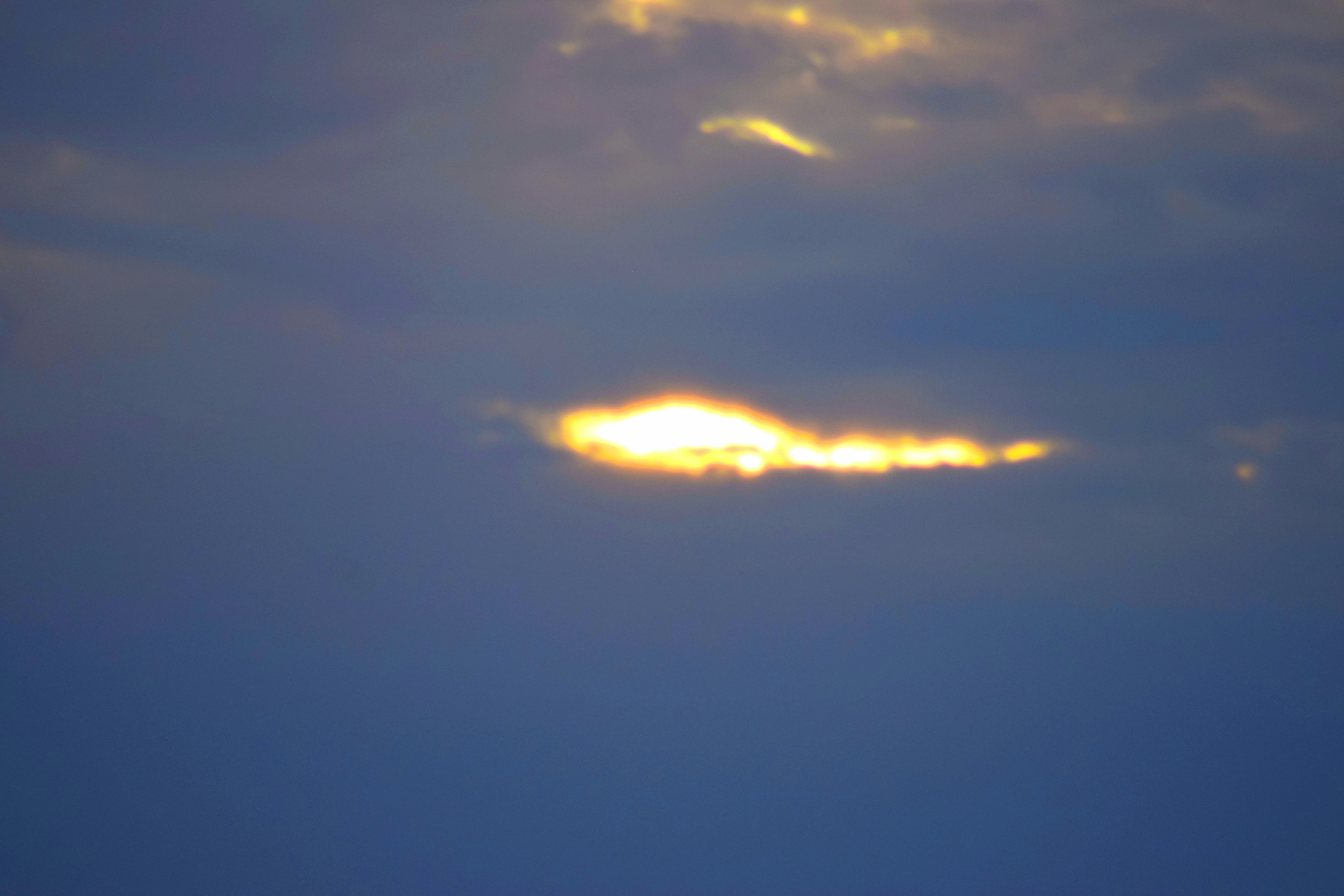 青い空に浮かぶ雲の隙間から差し込む光