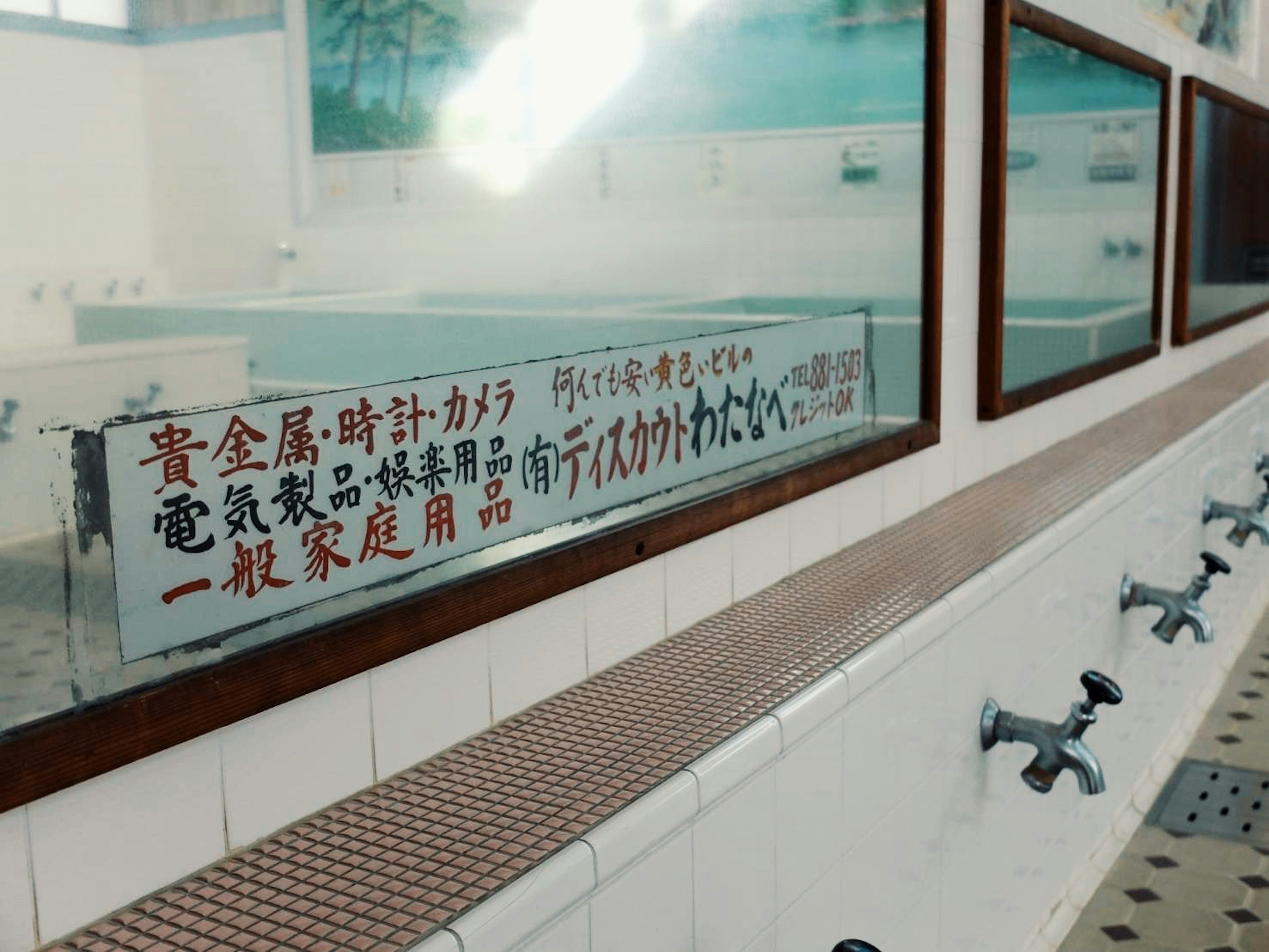 Interior view of a bathroom with sinks and mirrors featuring a Japanese notice on the wall