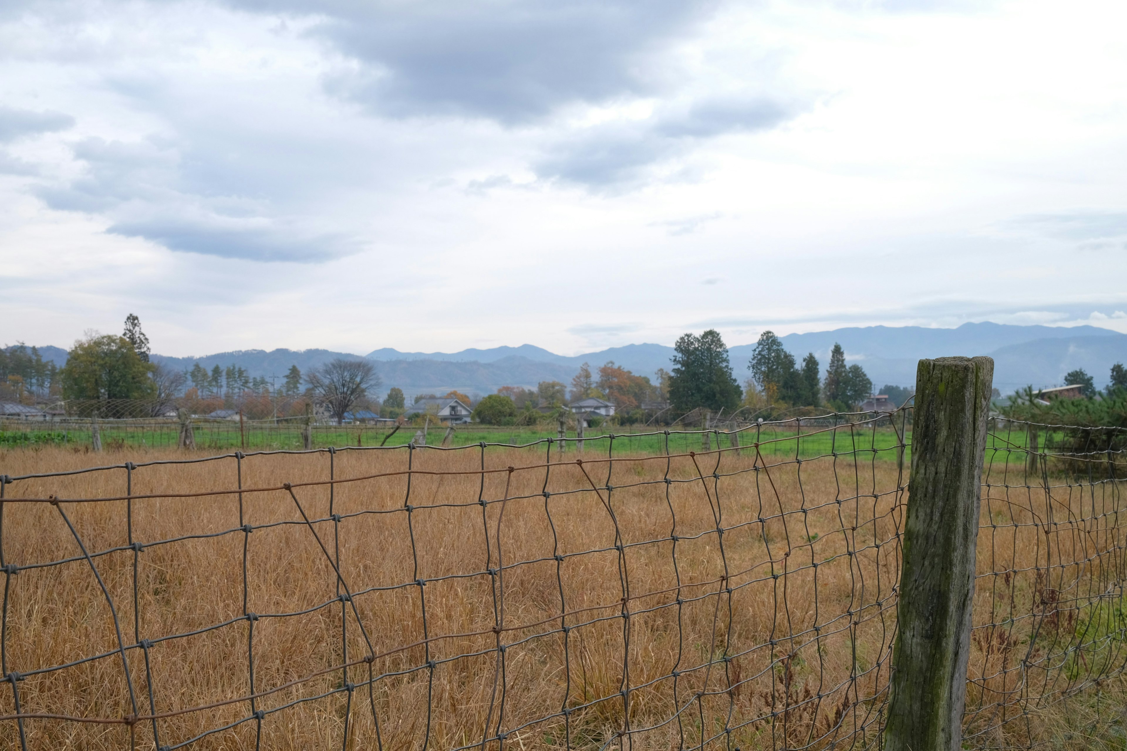 Paisaje rural pintoresco con montañas y una cerca de alambre de espino en primer plano