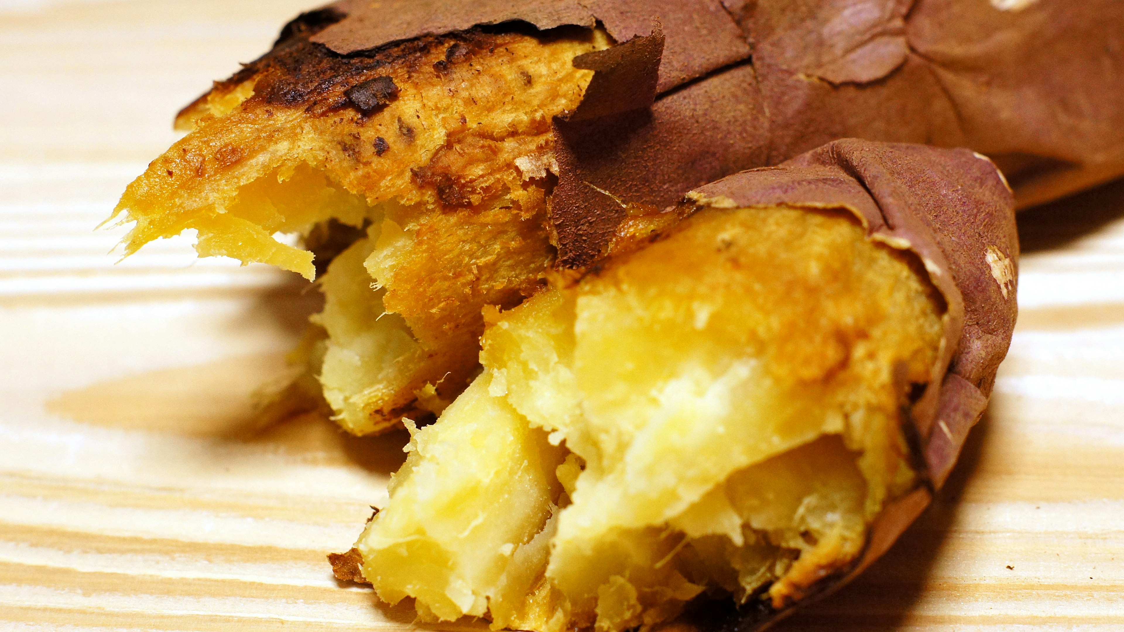 Primer plano de una batata asada envuelta en papel marrón mostrando un interior dorado