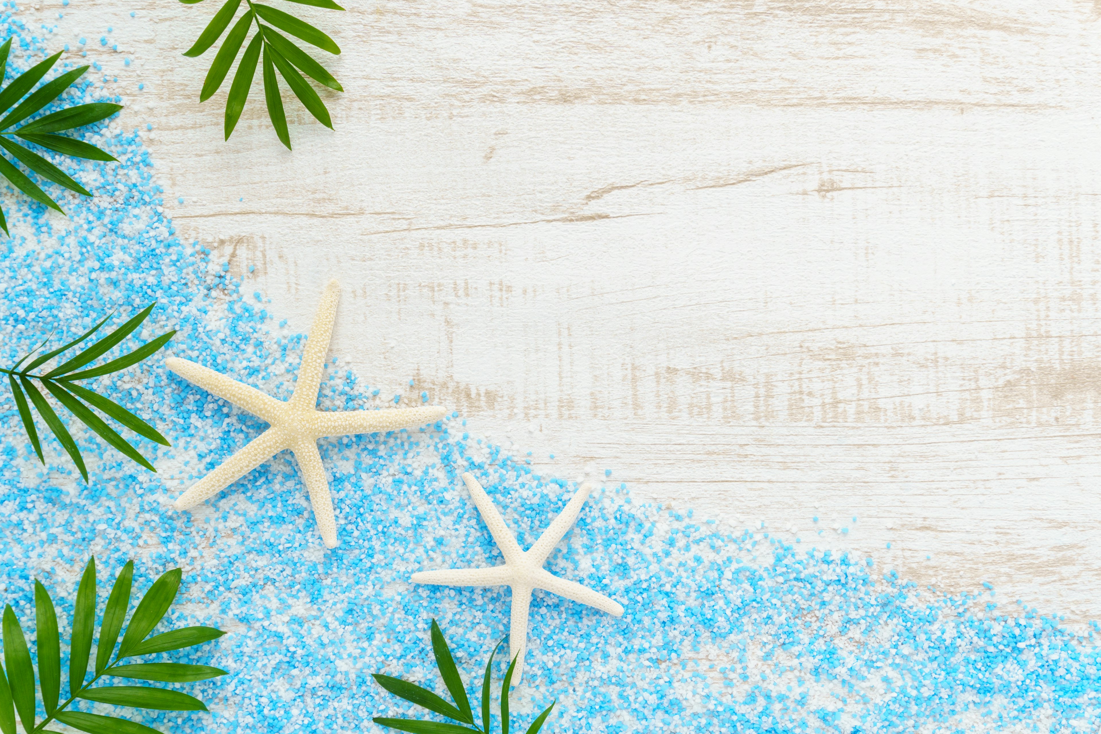 Sable bleu avec des étoiles de mer et des feuilles vertes éparpillées sur une surface en bois