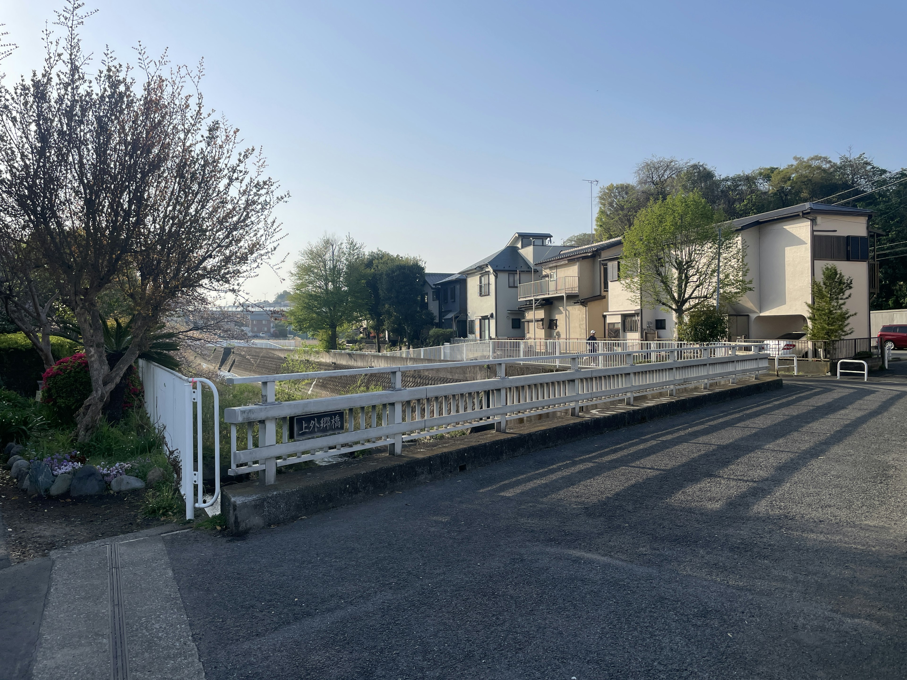 A quiet residential area featuring a white fence and green trees