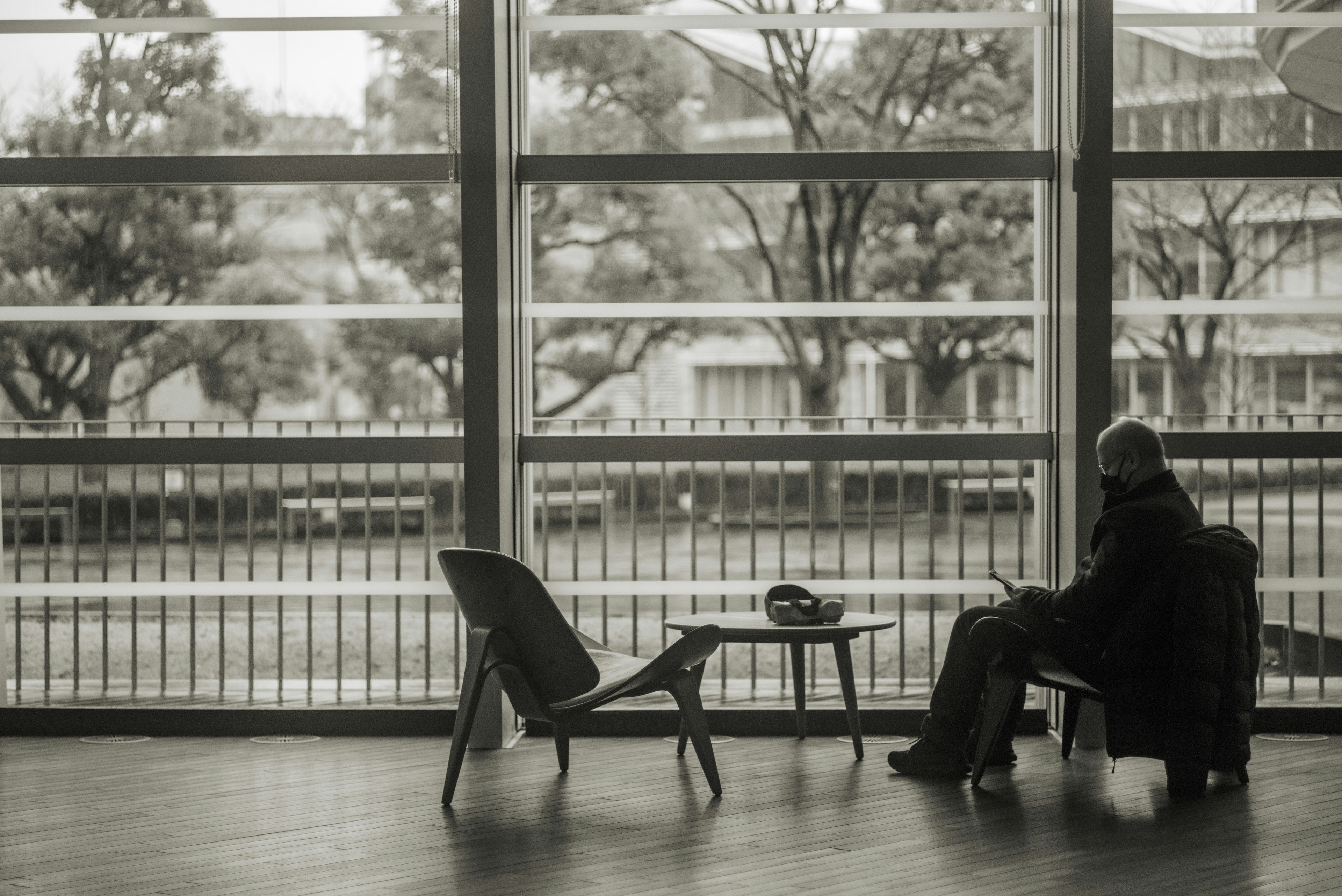 A person sitting in a quiet indoor space with simple furniture silhouettes