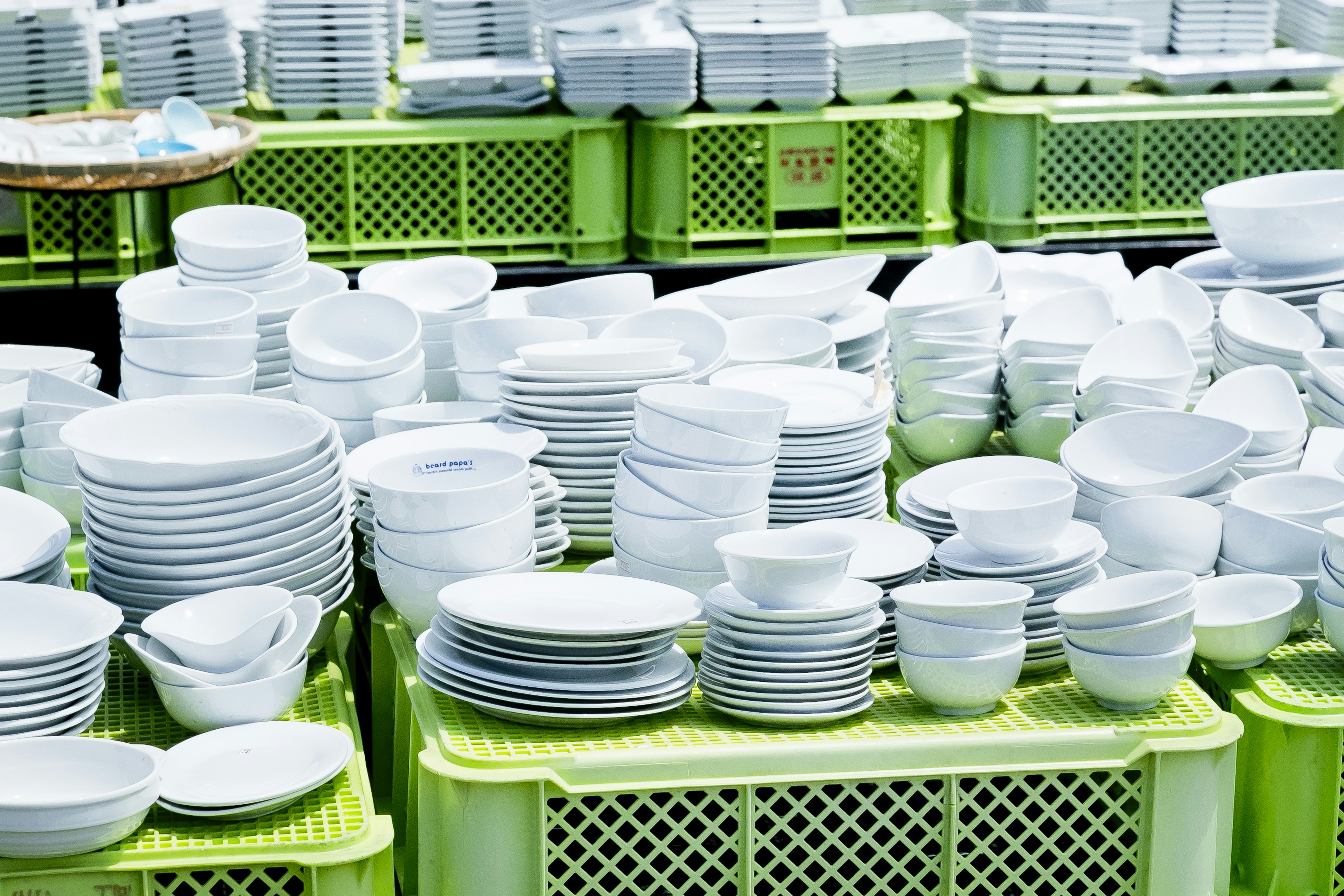 A collection of white plates and bowls stacked on green crates