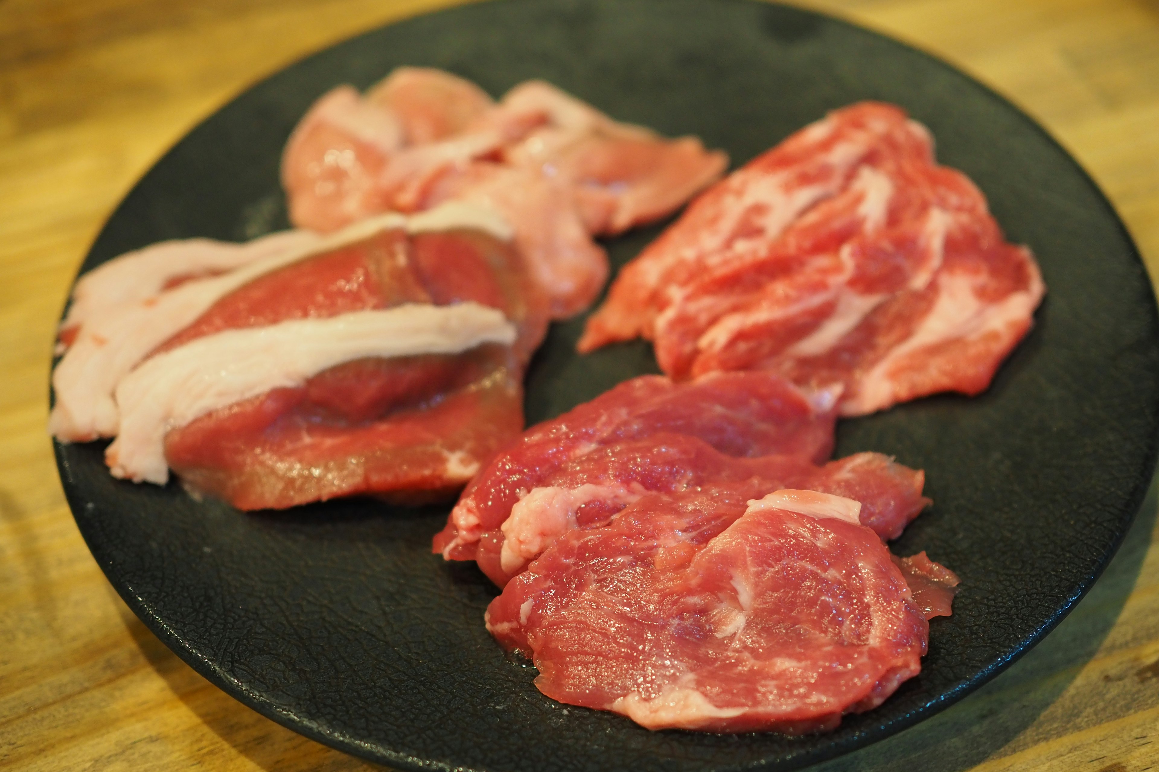 Various types of raw meat arranged on a black plate