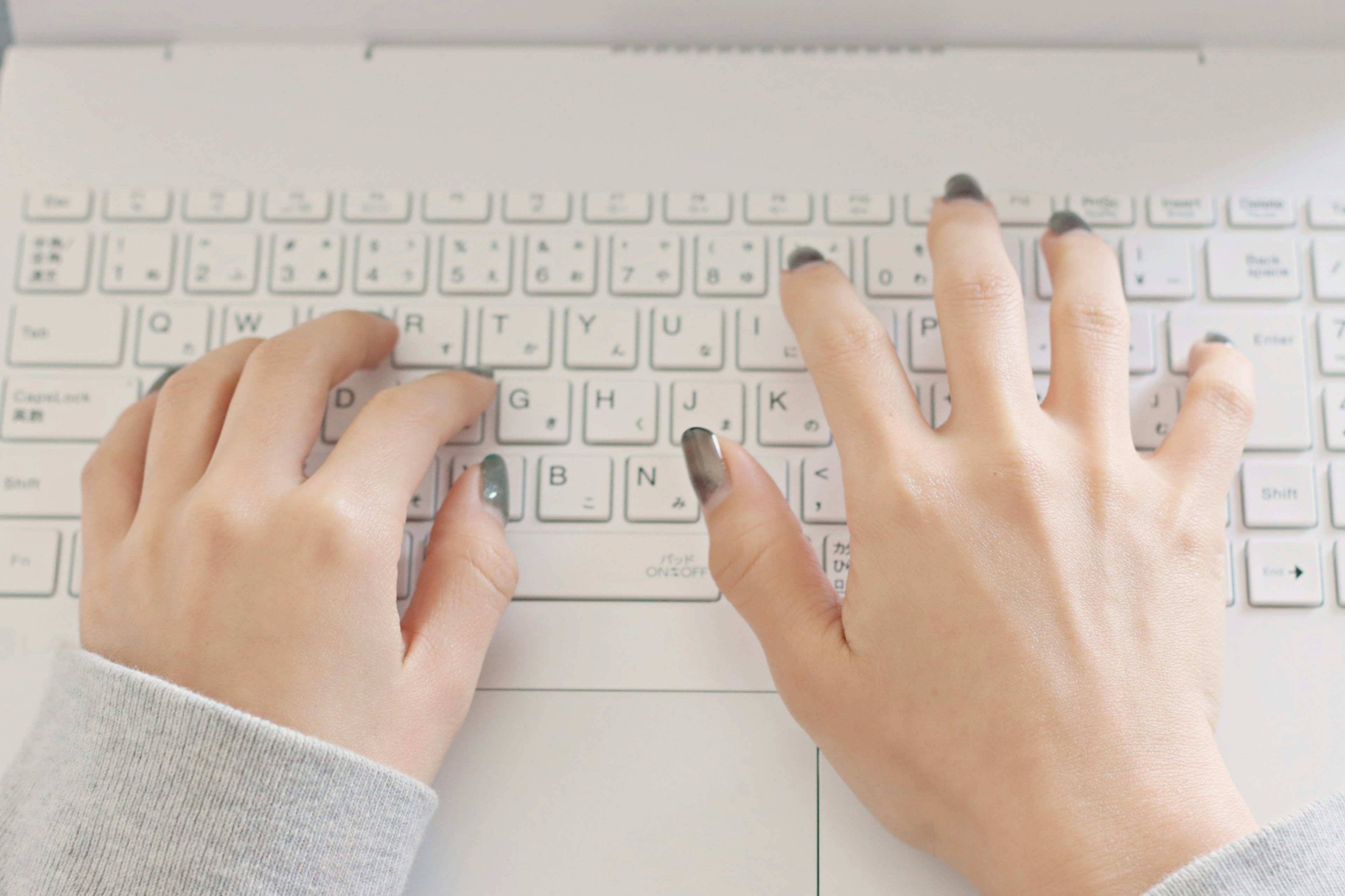 Manos escribiendo en un teclado de computadora portátil blanco