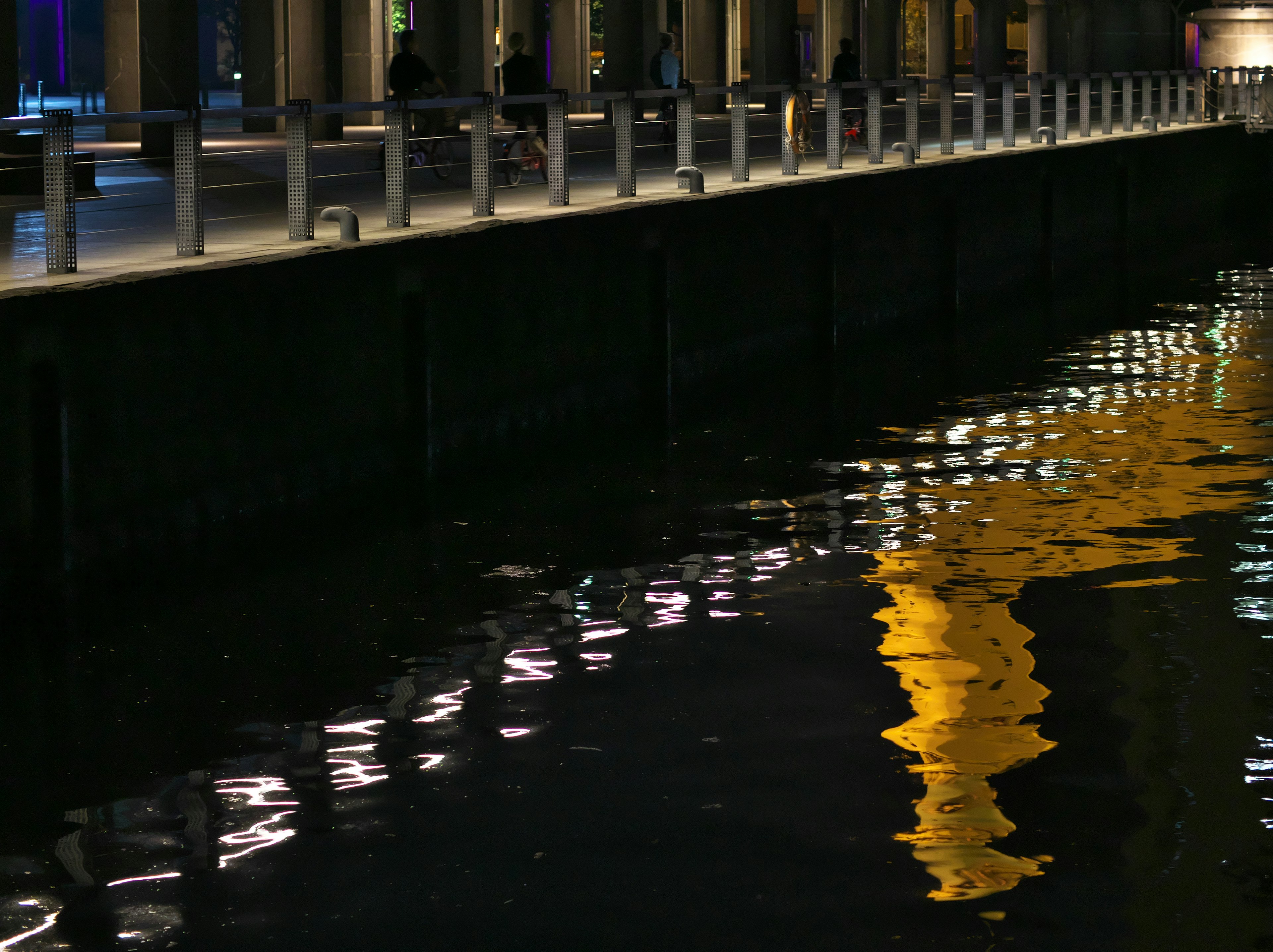 夜の水面に映る黄色い光と反射する建物の柱