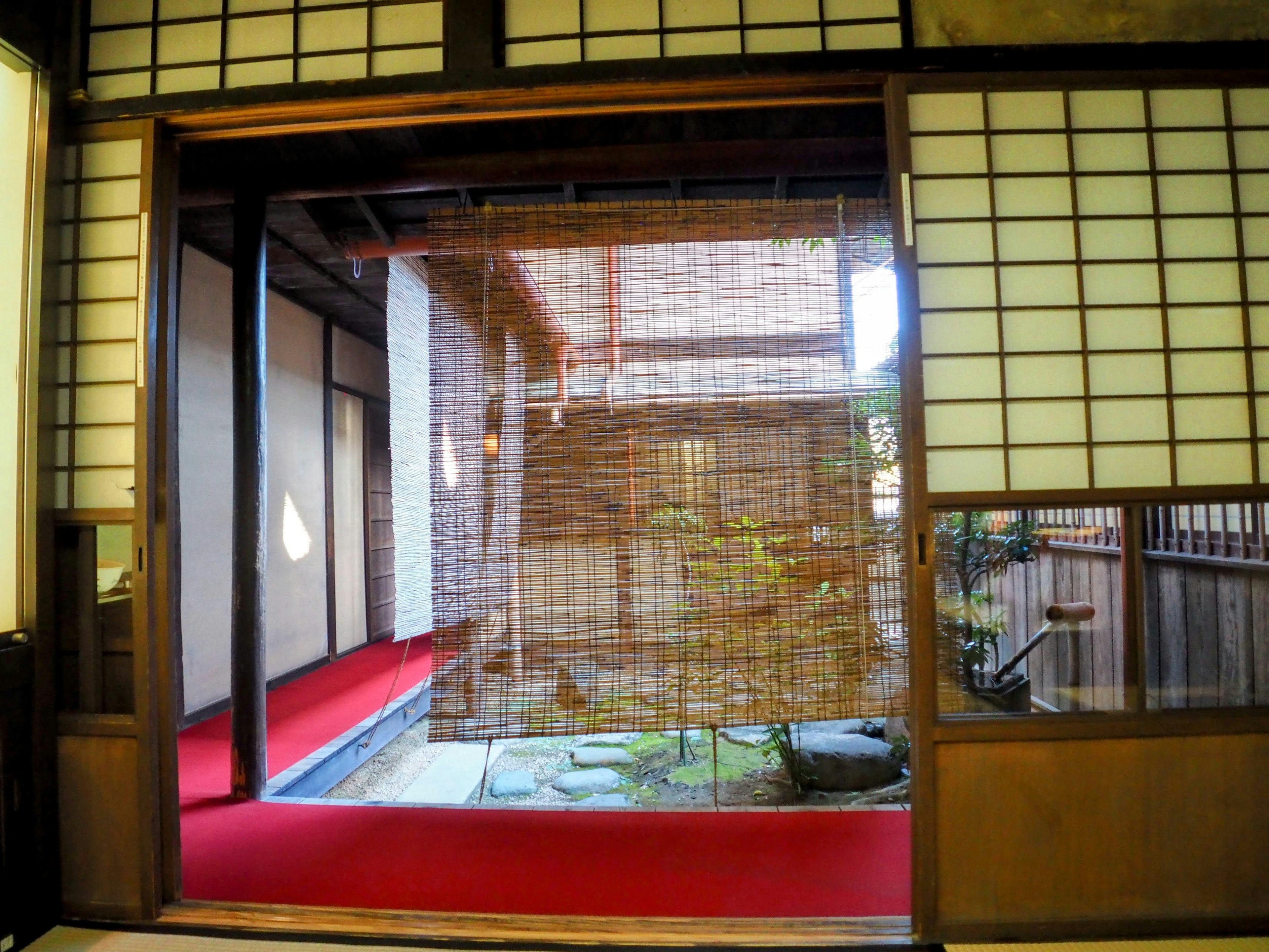 Vue de l'intérieur d'une maison japonaise traditionnelle avec une cour visible à travers des écrans shoji et un sol en tatami