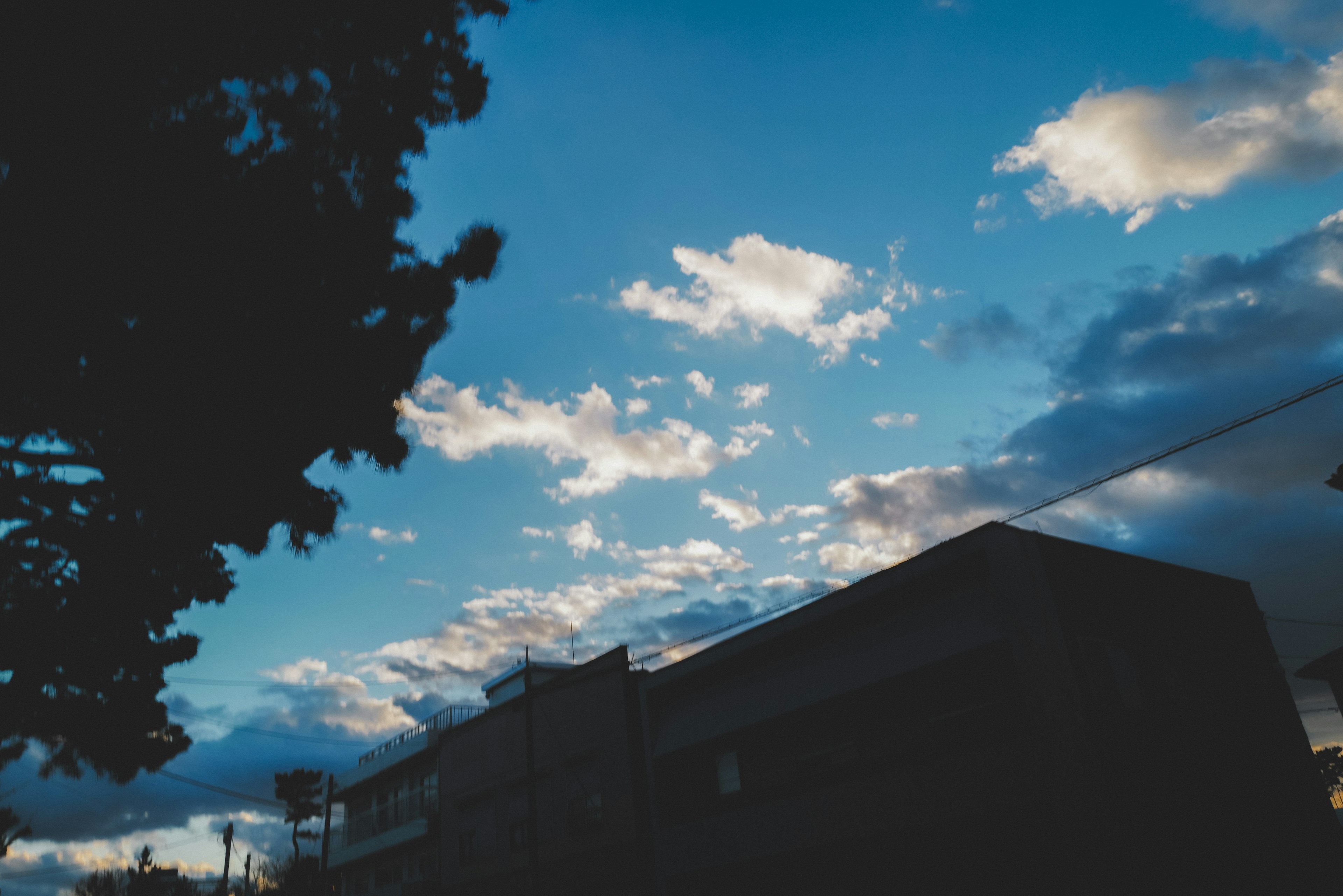 青空と雲が広がる夕方の風景 照明の影響で建物のシルエットが際立つ