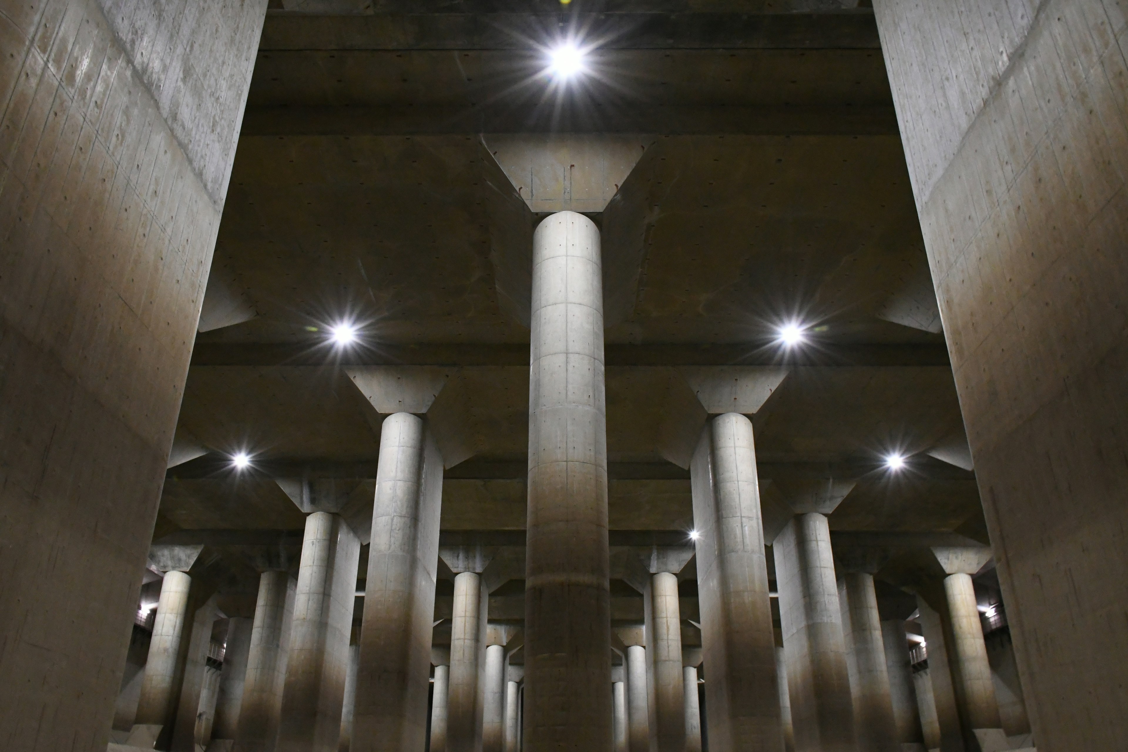 コンクリートの柱と天井の照明がある地下空間の写真