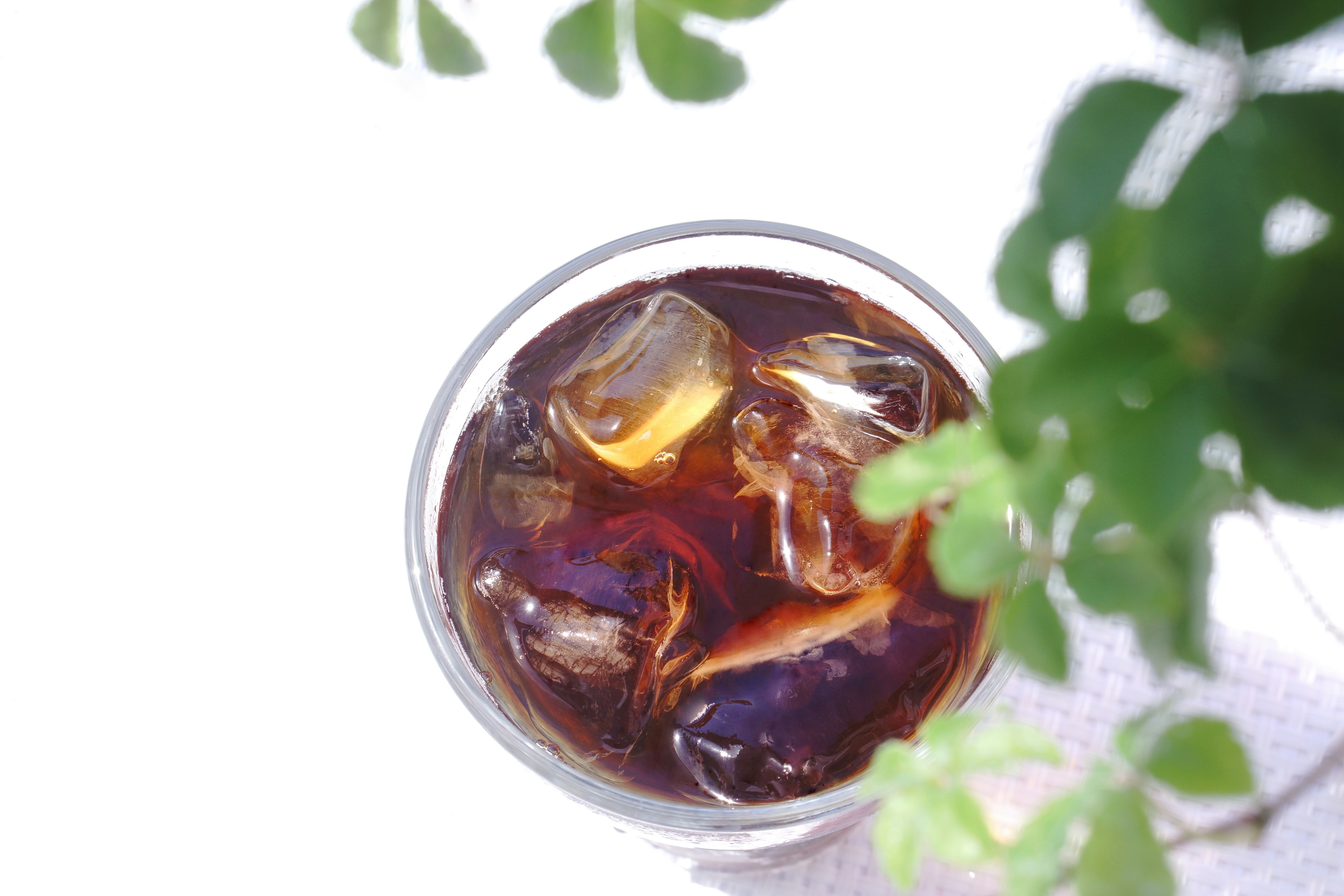 Glass of iced tea with ice cubes and green leaves