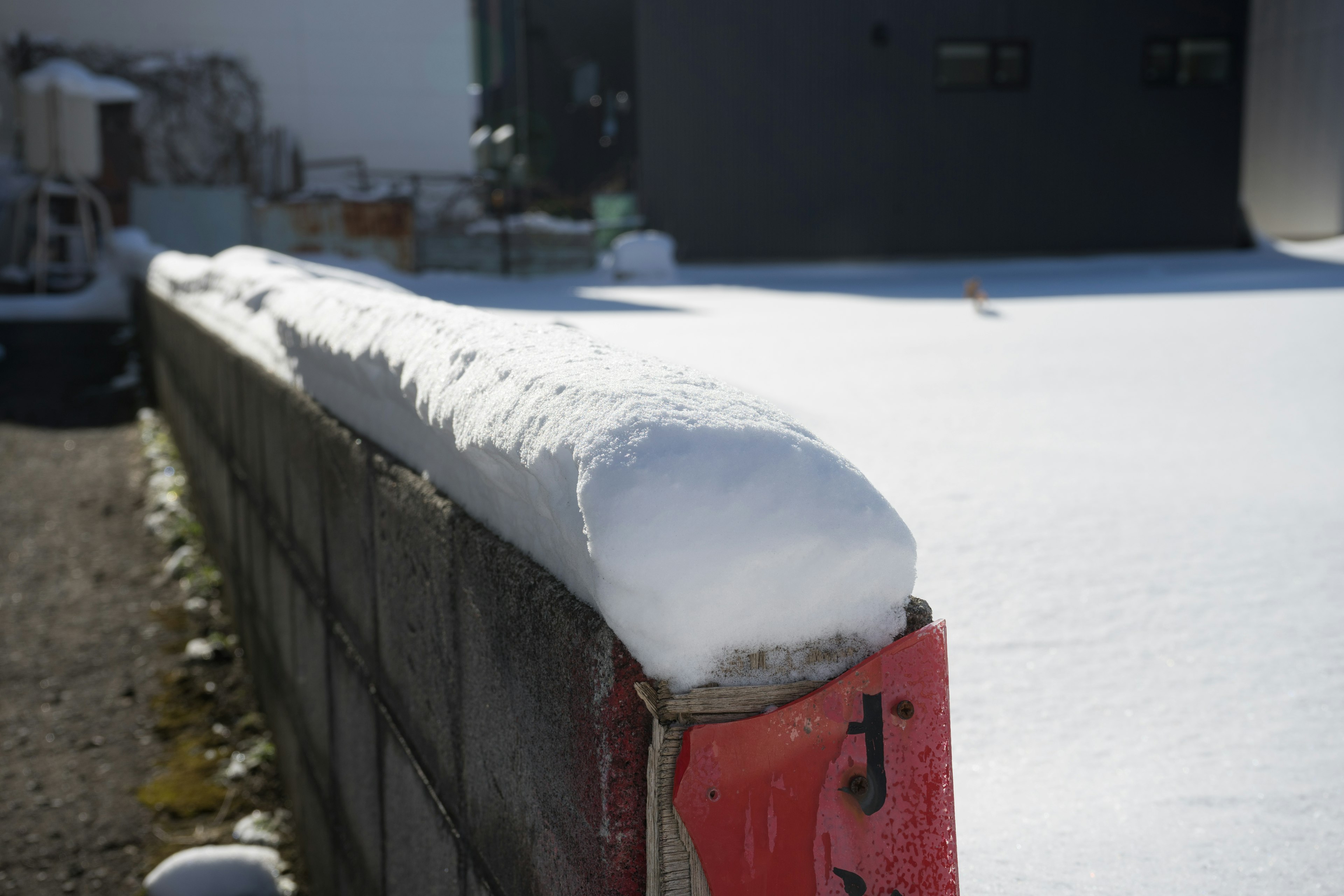 Snow covering the top of a block wall with a clear blue sky