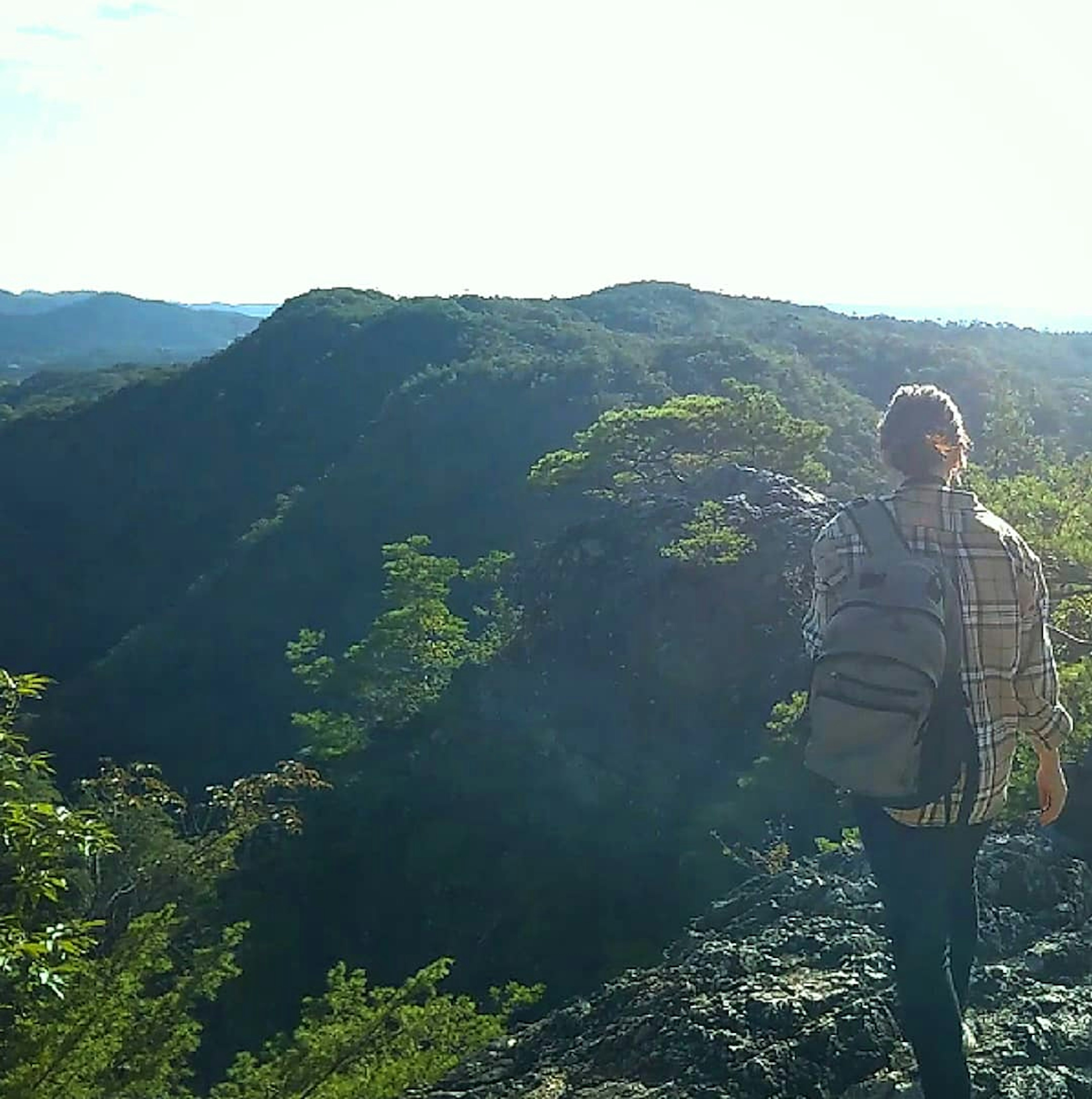 Seseorang berdiri di puncak gunung melihat pemandangan yang indah