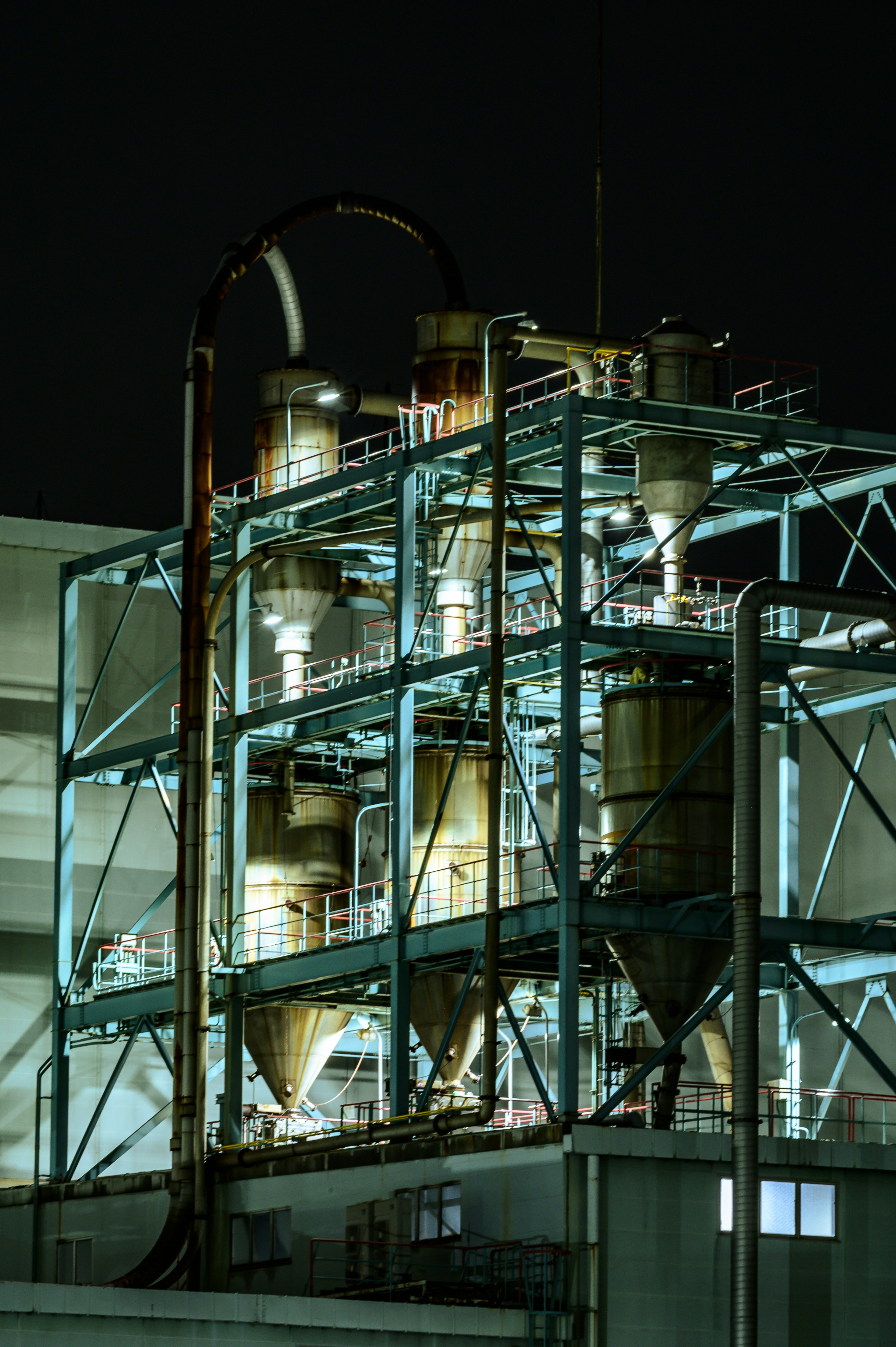 Nighttime view of industrial tanks and piping structure