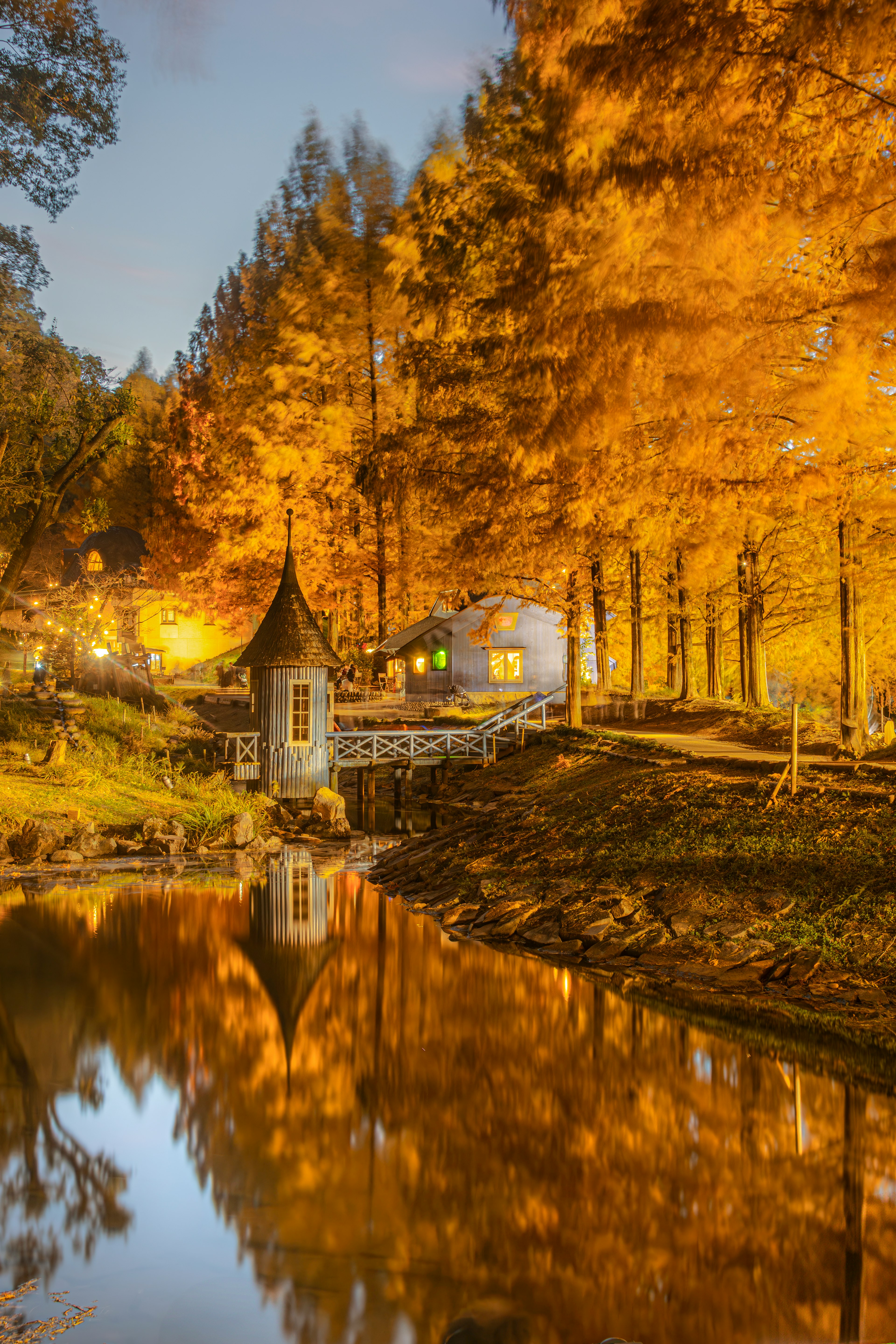 Malersicher Blick auf eine Hütte am Teich umgeben von herbstlich gefärbten Bäumen