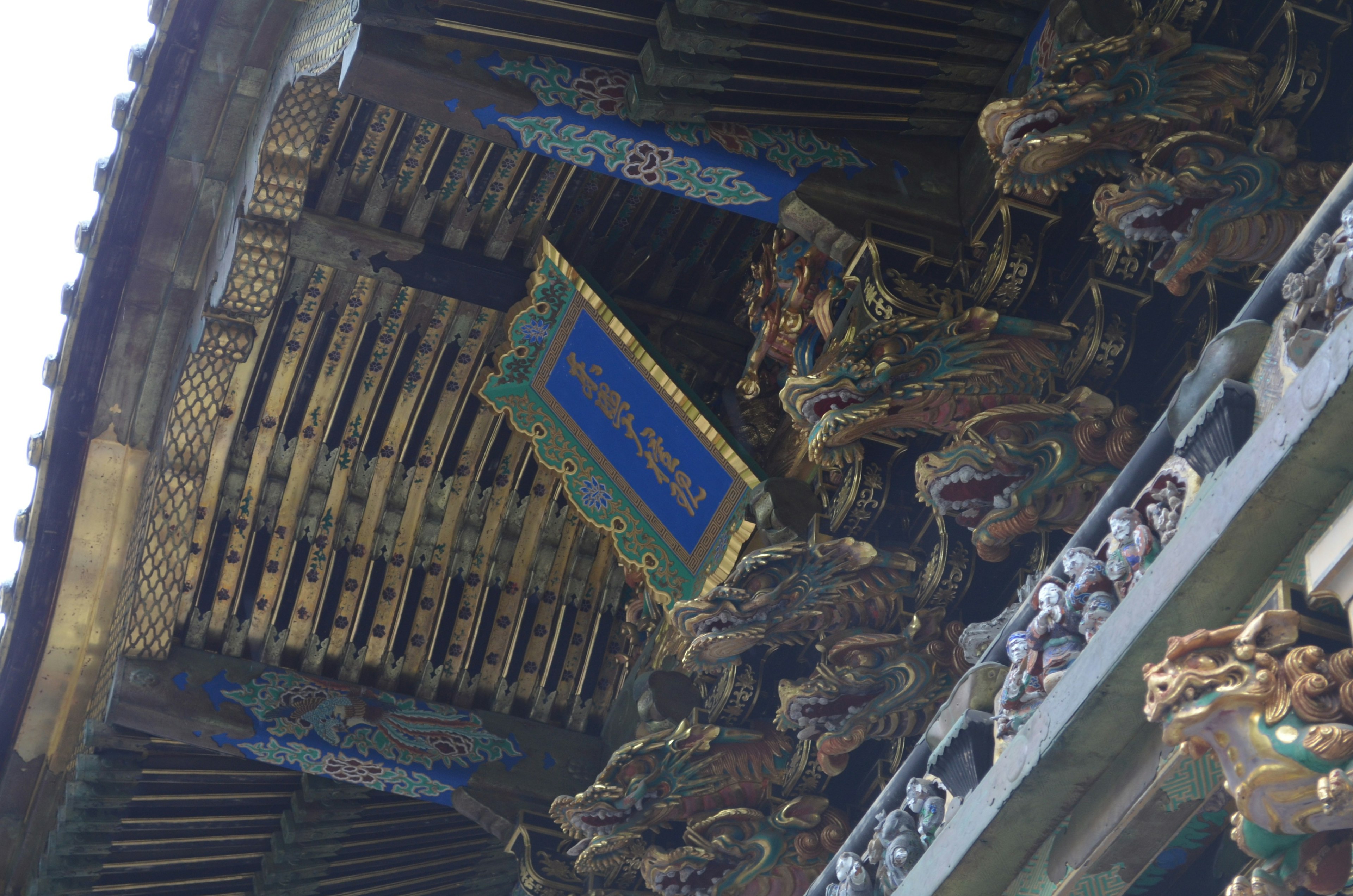 Ornately carved roof with a blue sign hanging beneath