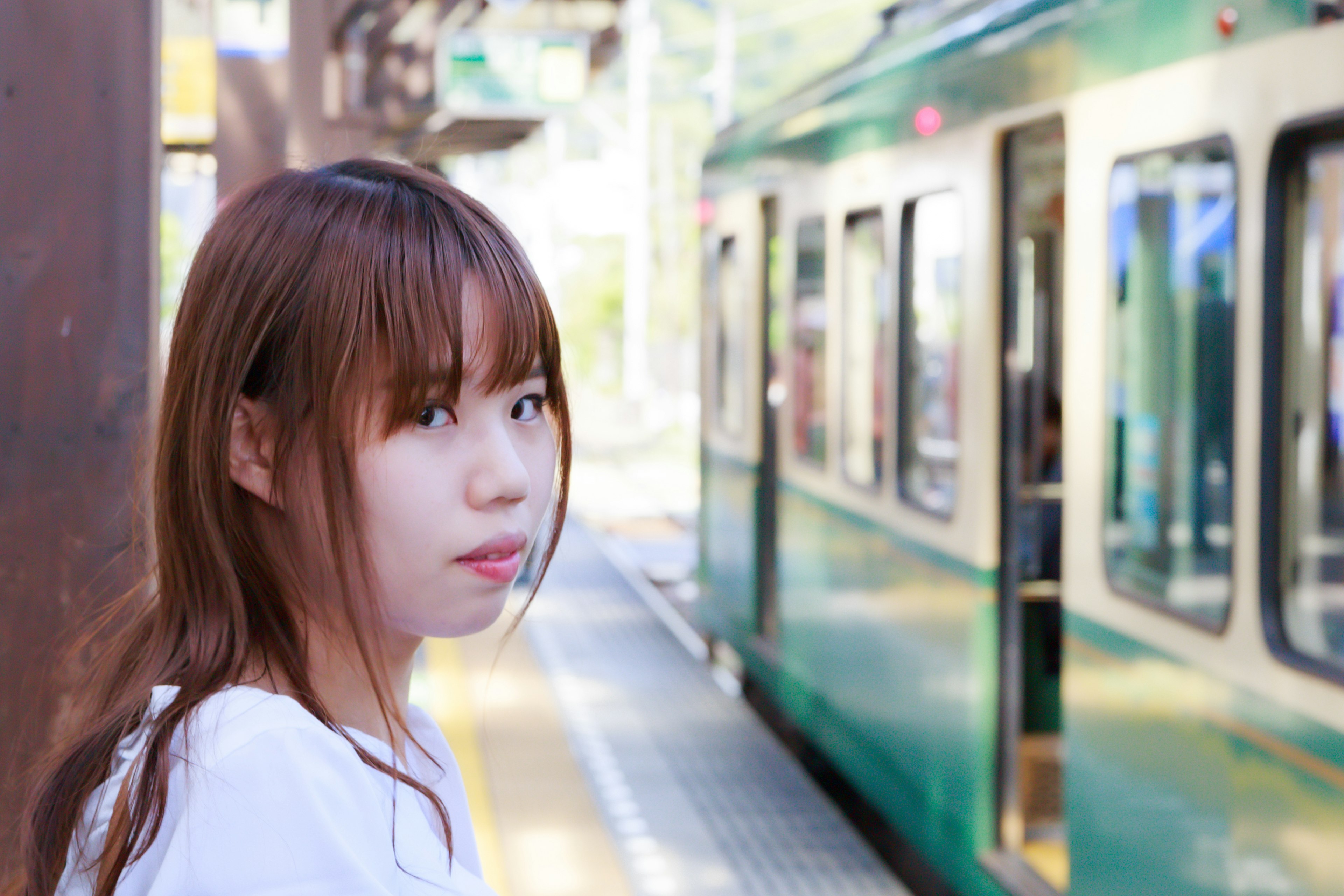 Mujer esperando en la plataforma del tren con un tren verde