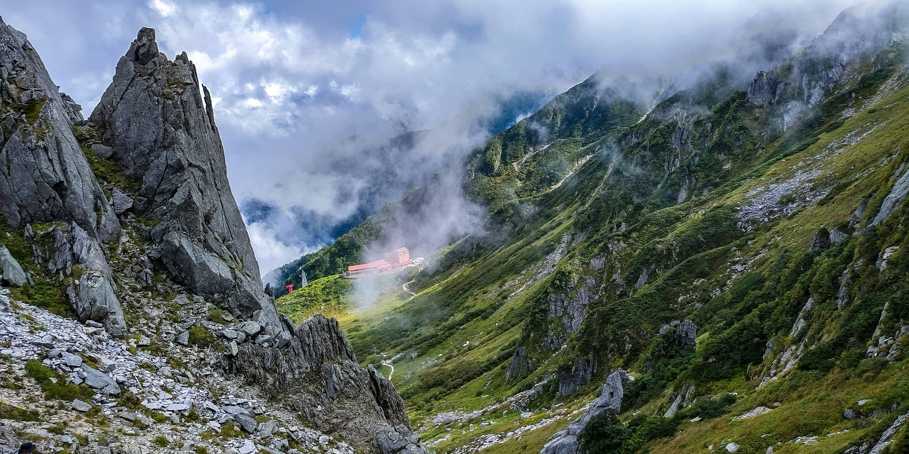 Vallée de montagne pittoresque avec des sommets rocheux et une verdure luxuriante sous un ciel nuageux