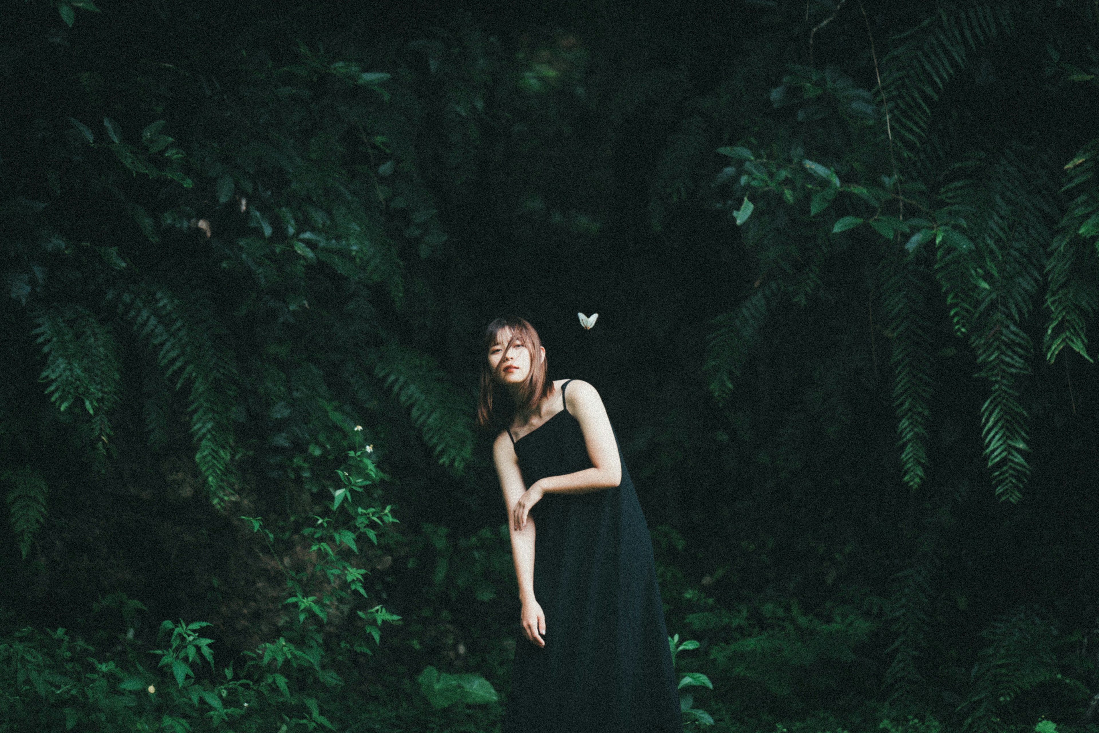 A woman in a black dress standing against a green background