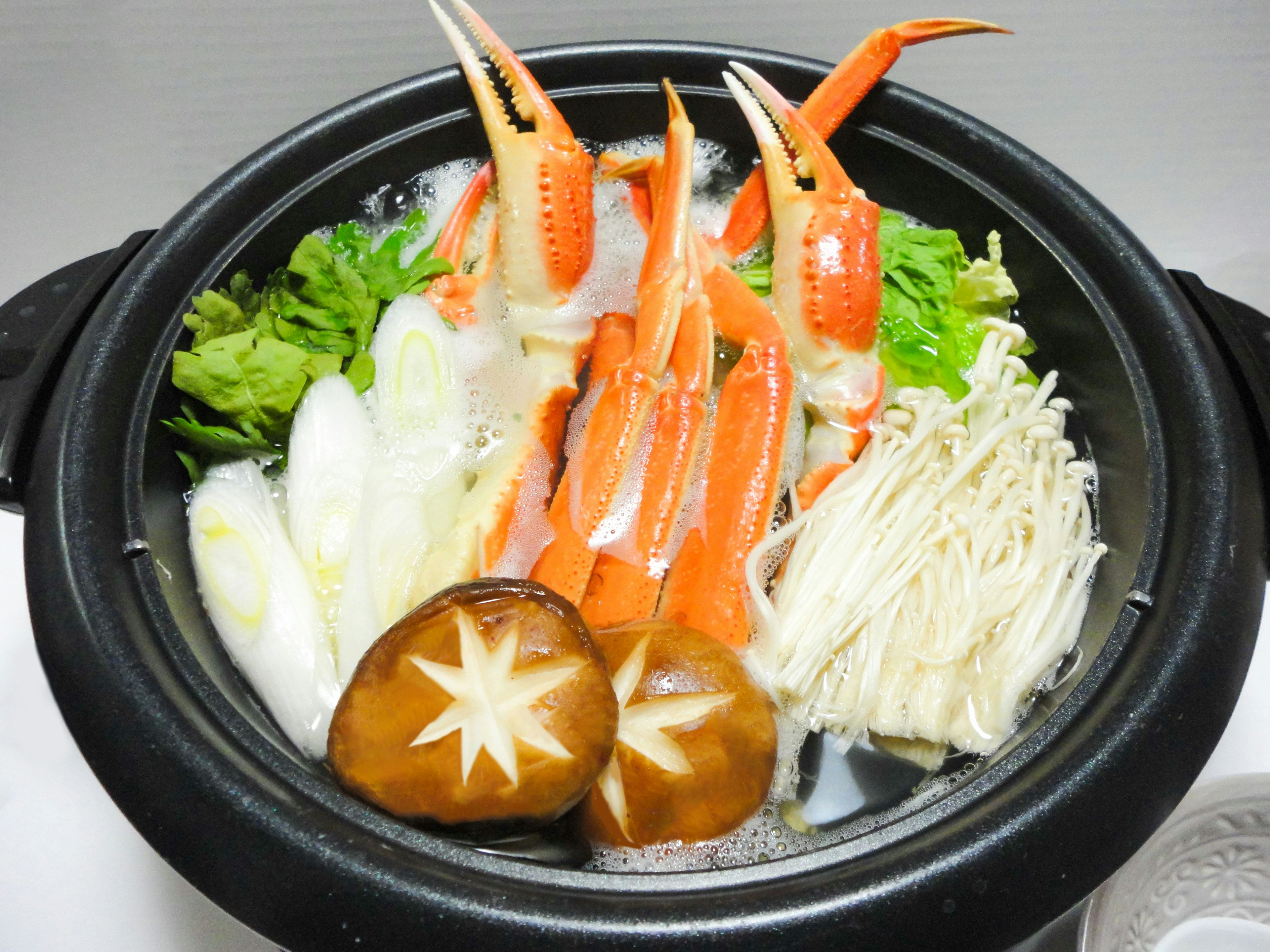 A pot filled with crab, vegetables, and mushrooms for a hot pot dish