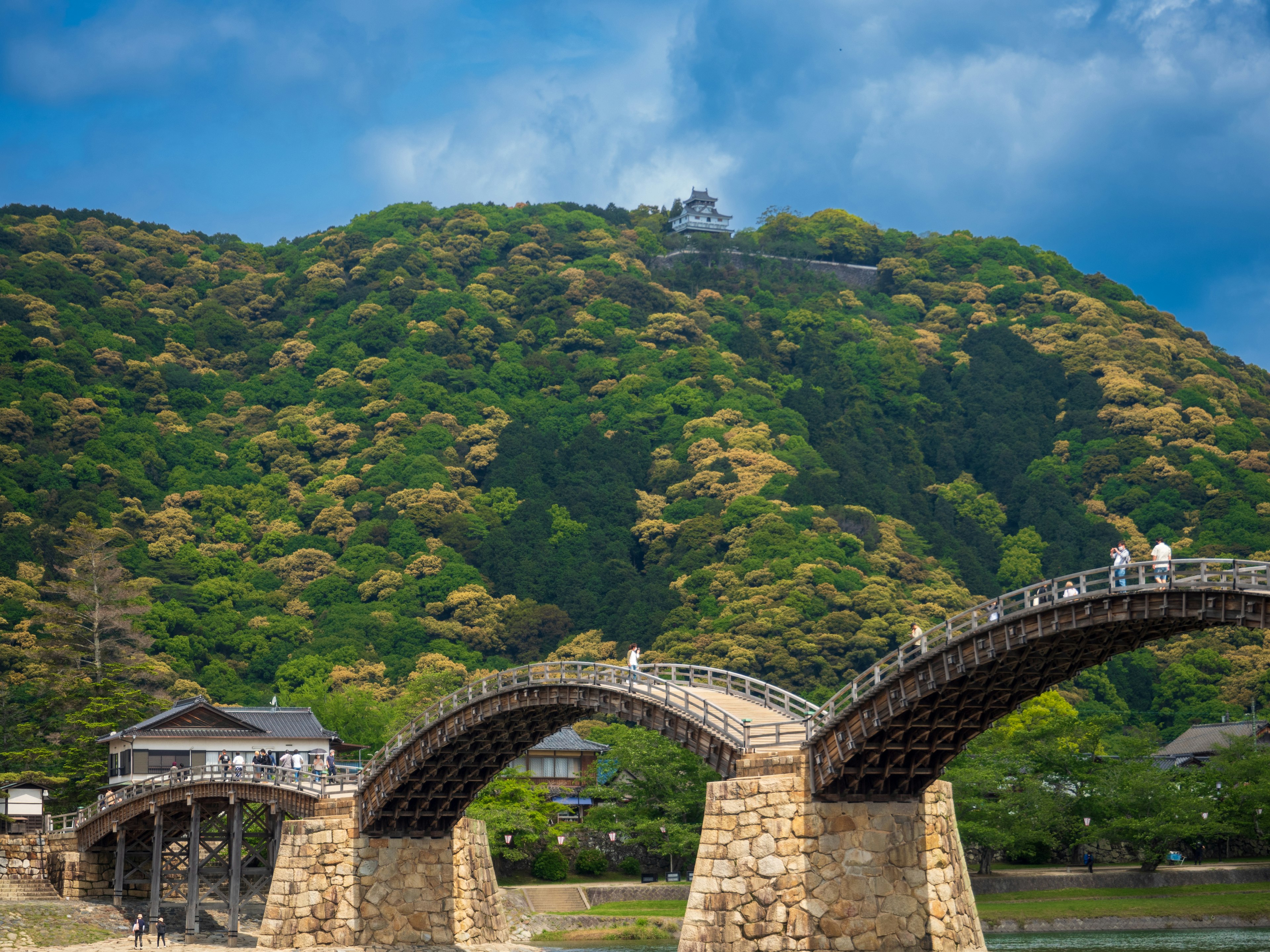 Kintai-Brücke in Iwakuni umgeben von üppigen grünen Hügeln und blauem Himmel