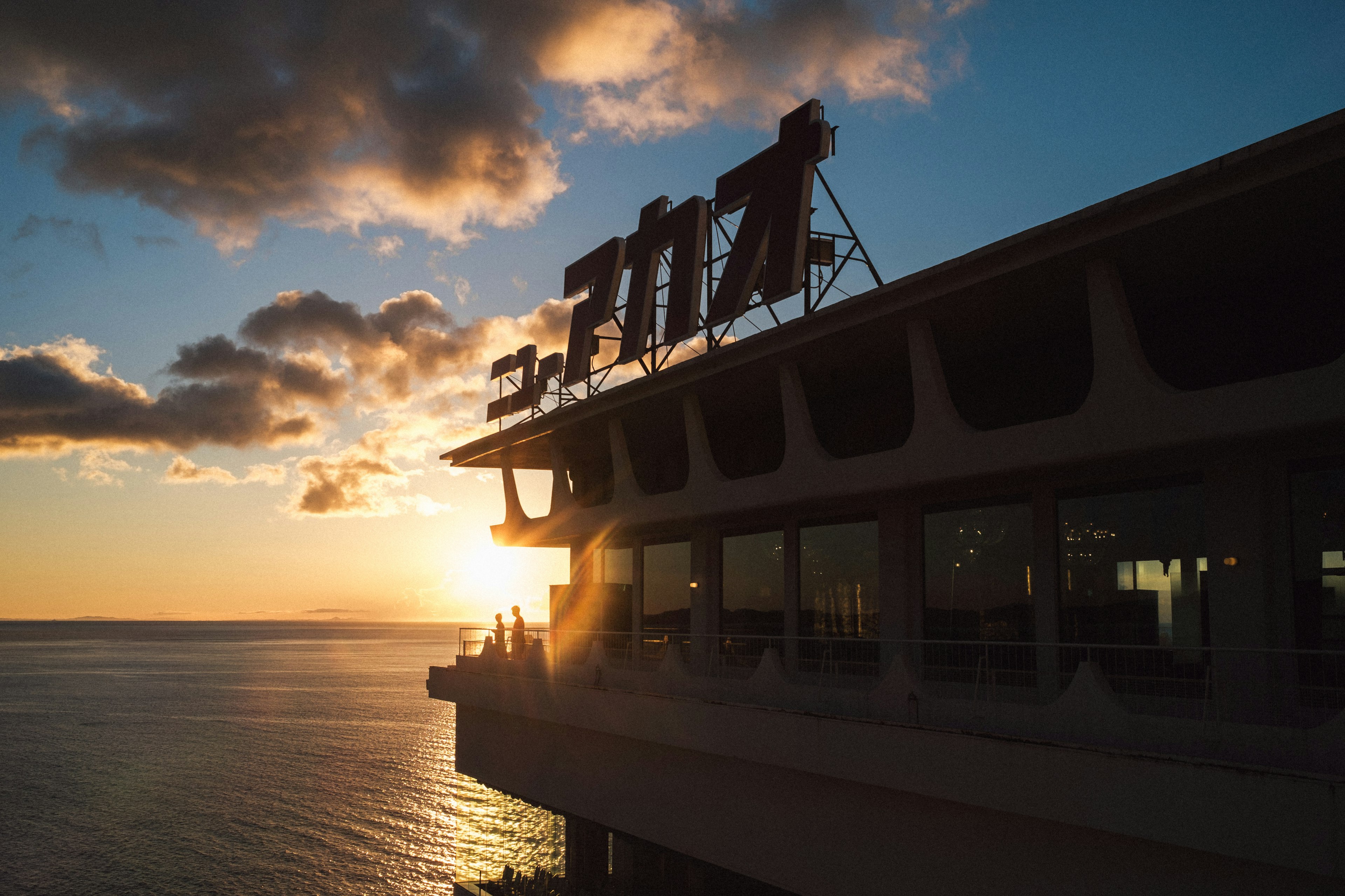 Vista esterna di un edificio con un grande cartello al tramonto