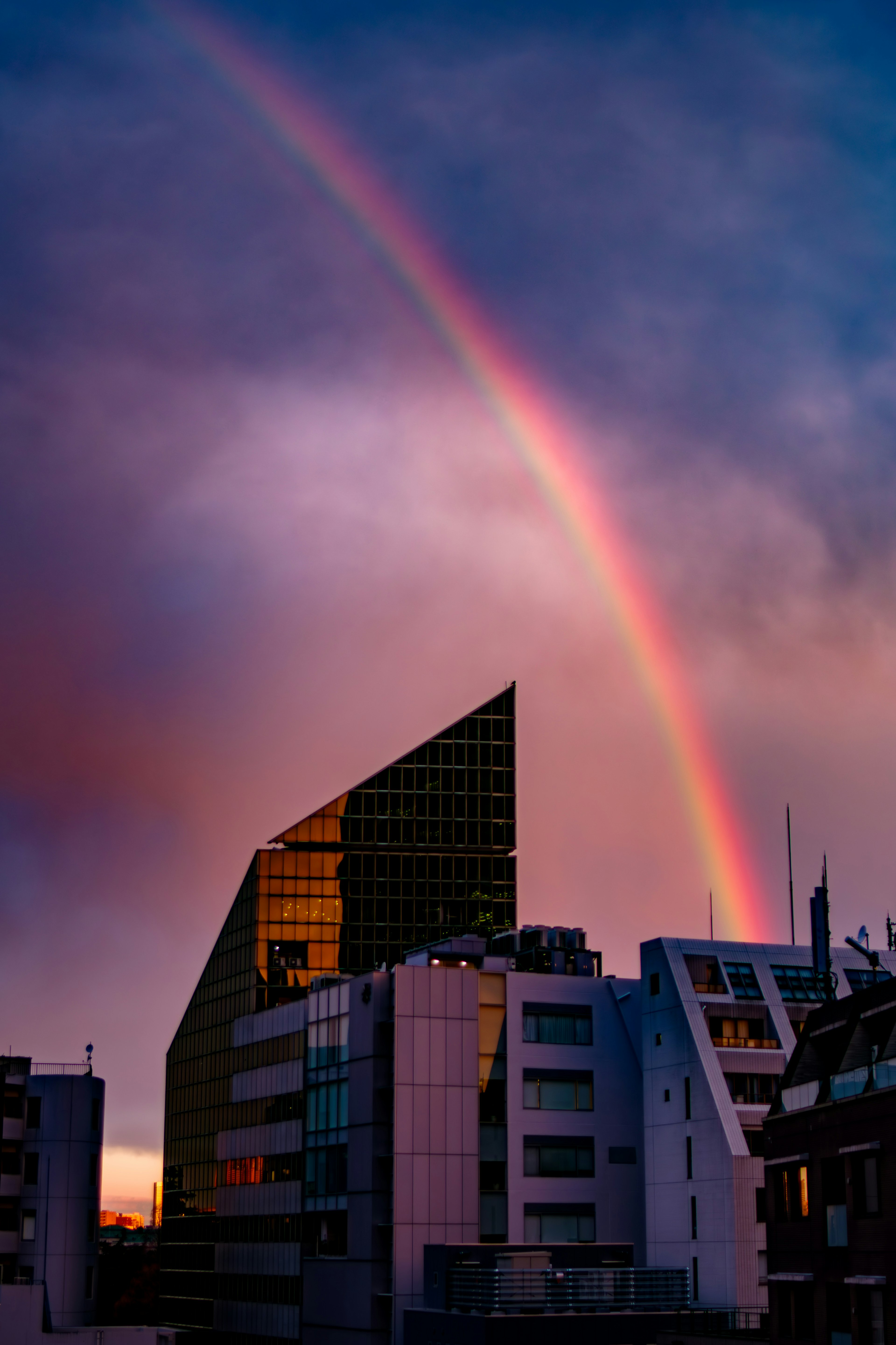 Regenbogen über modernen Gebäuden bei Sonnenuntergang