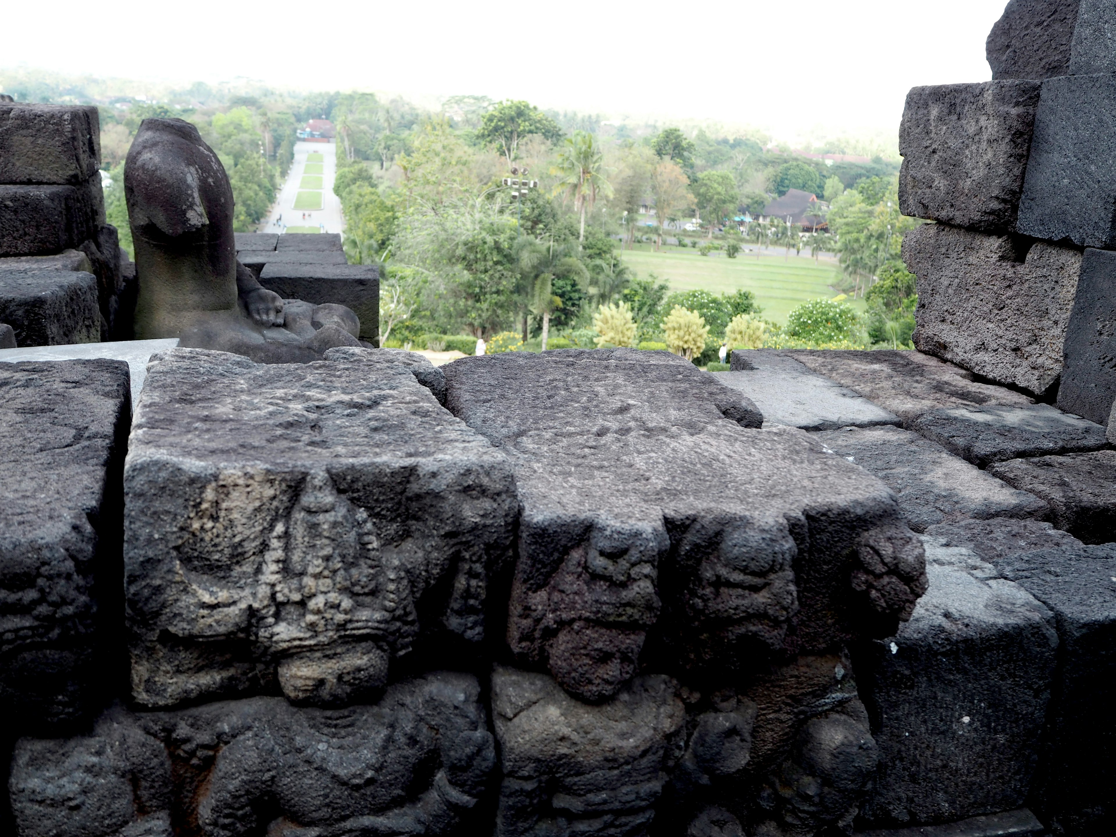 Stone carvings at Borobudur Temple with lush green surroundings