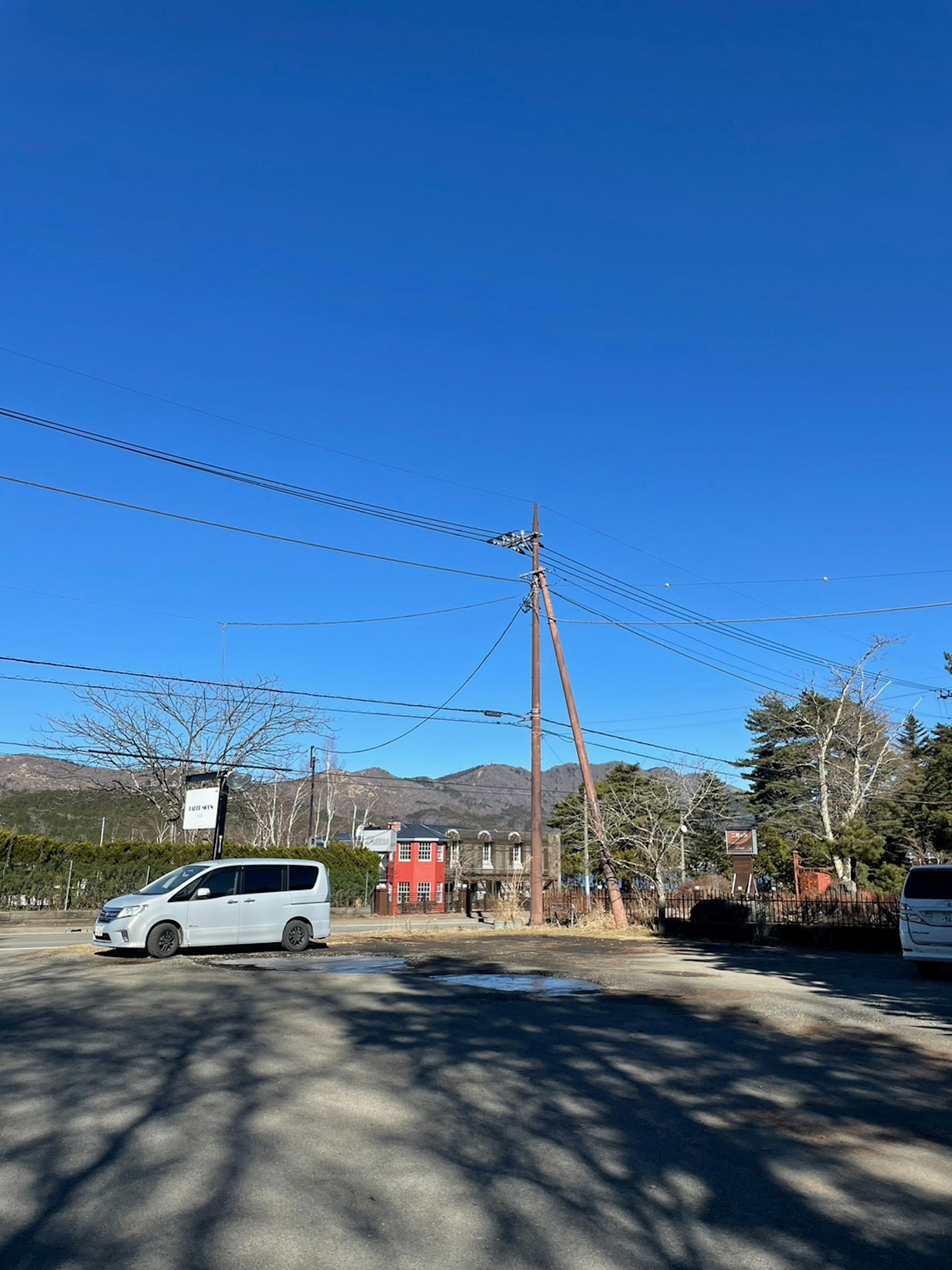 青空の下に立つ電柱と車両の風景