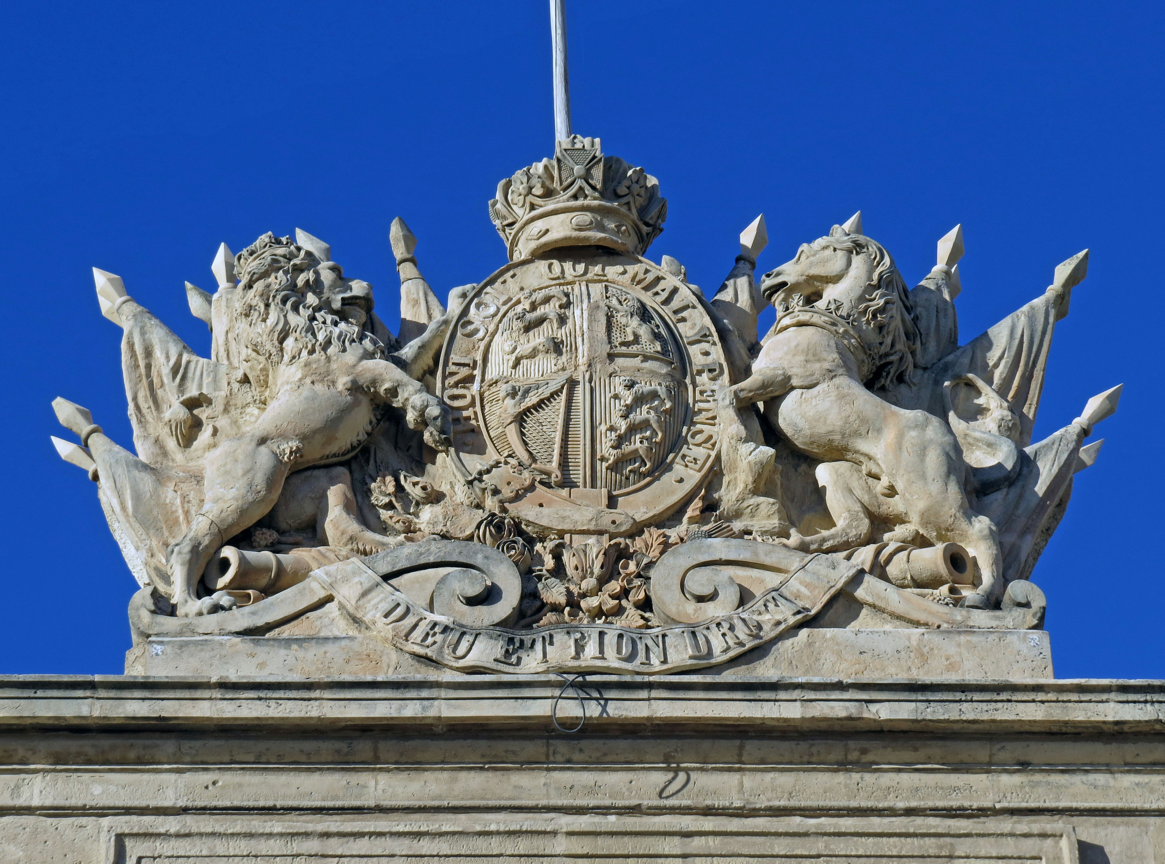 Steinernes Wappen mit Löwen und Krone vor blauem Himmel