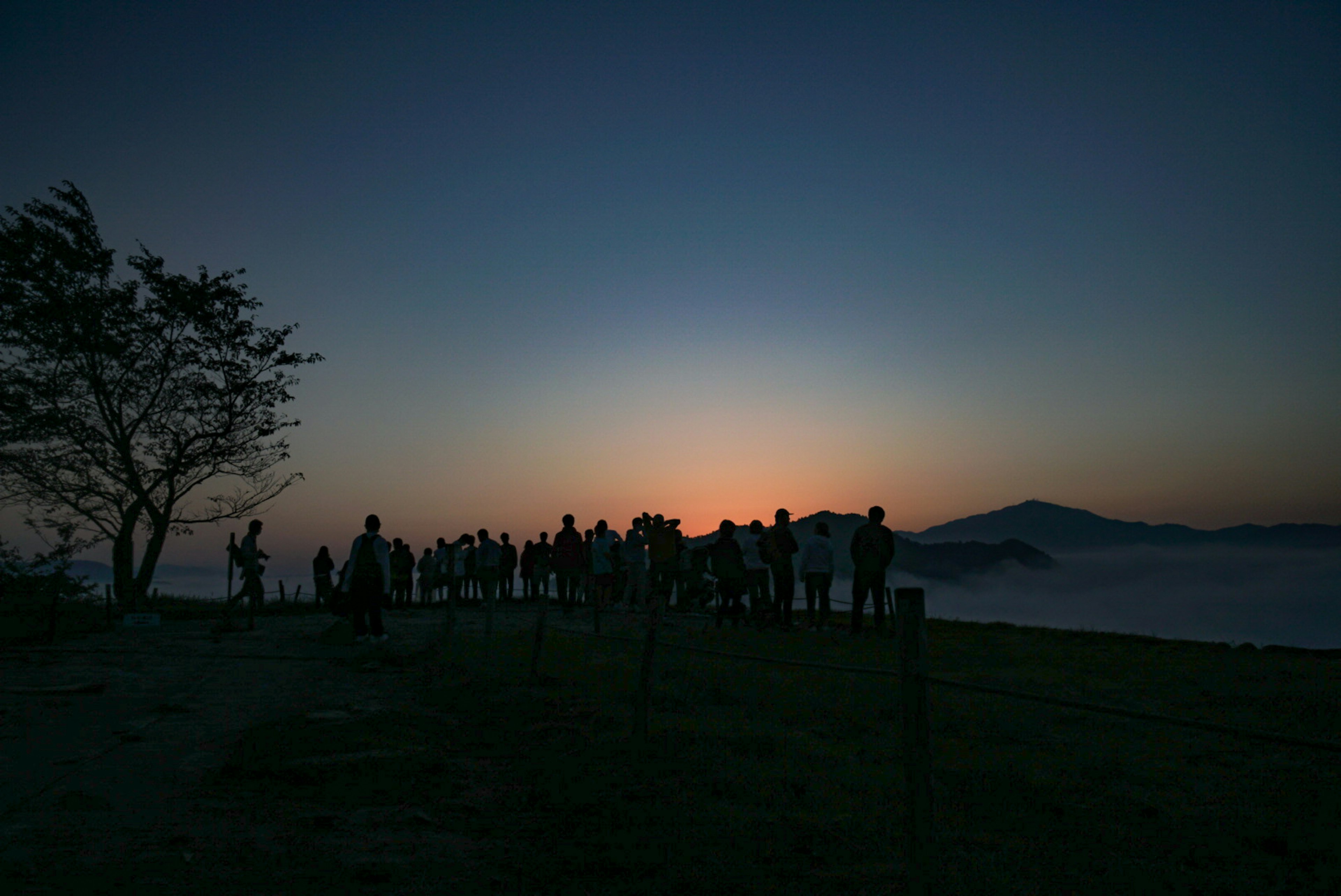 Silhouette of people watching the sunset with mountains in the background