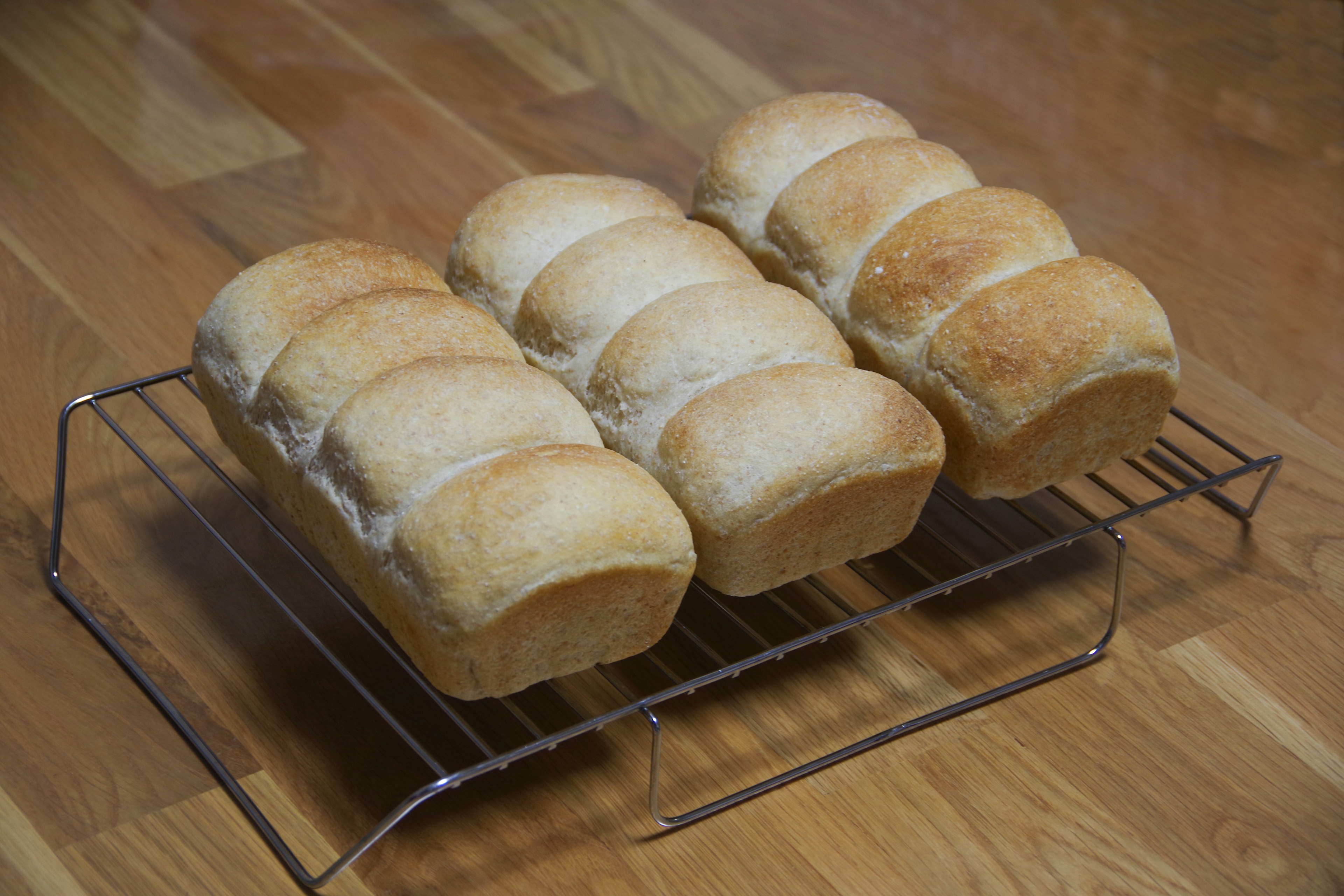 Freshly baked white bread loaves arranged on a cooling rack