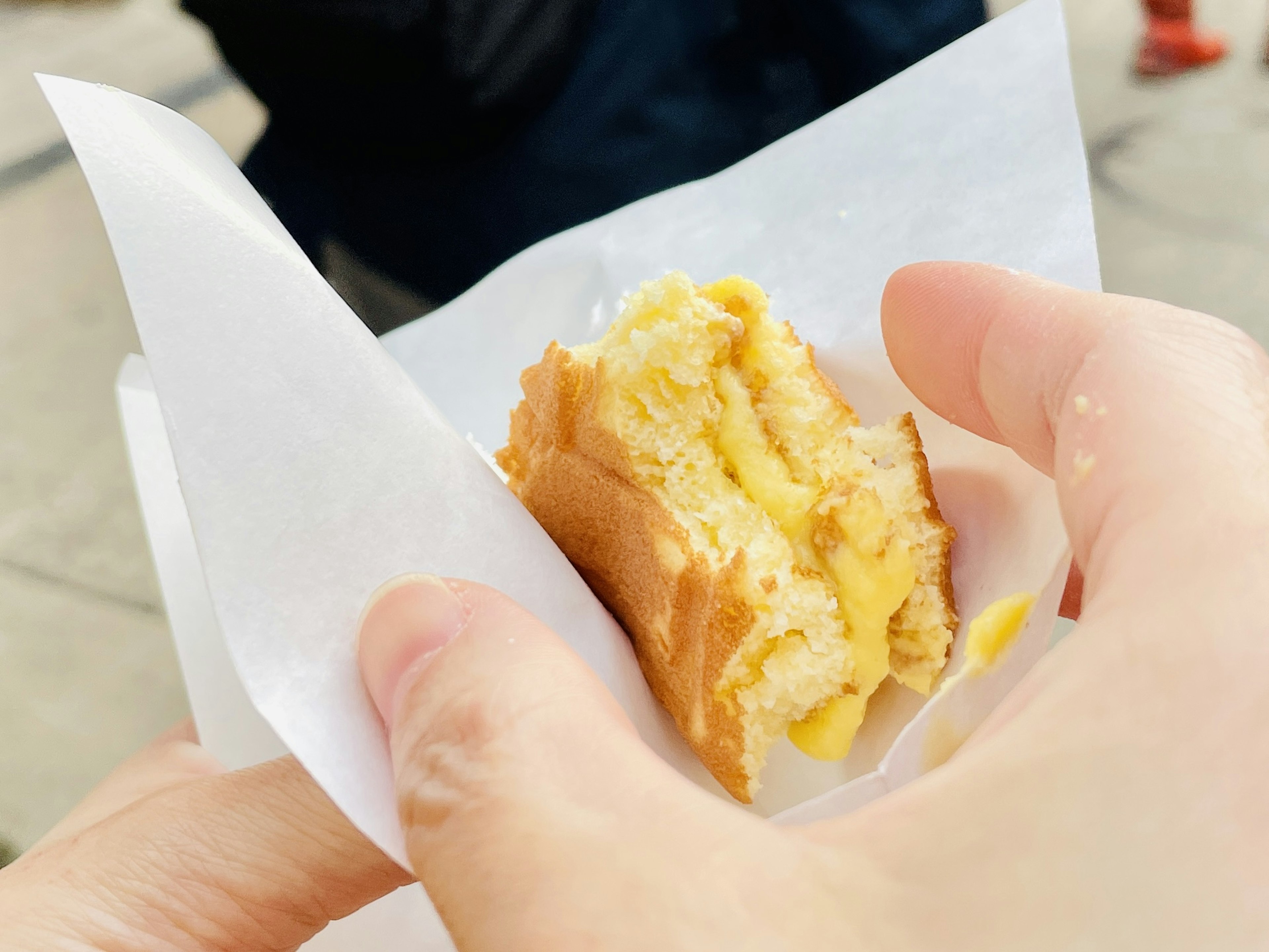 Primo piano di un dolce ripieno di crema tenuto in mano