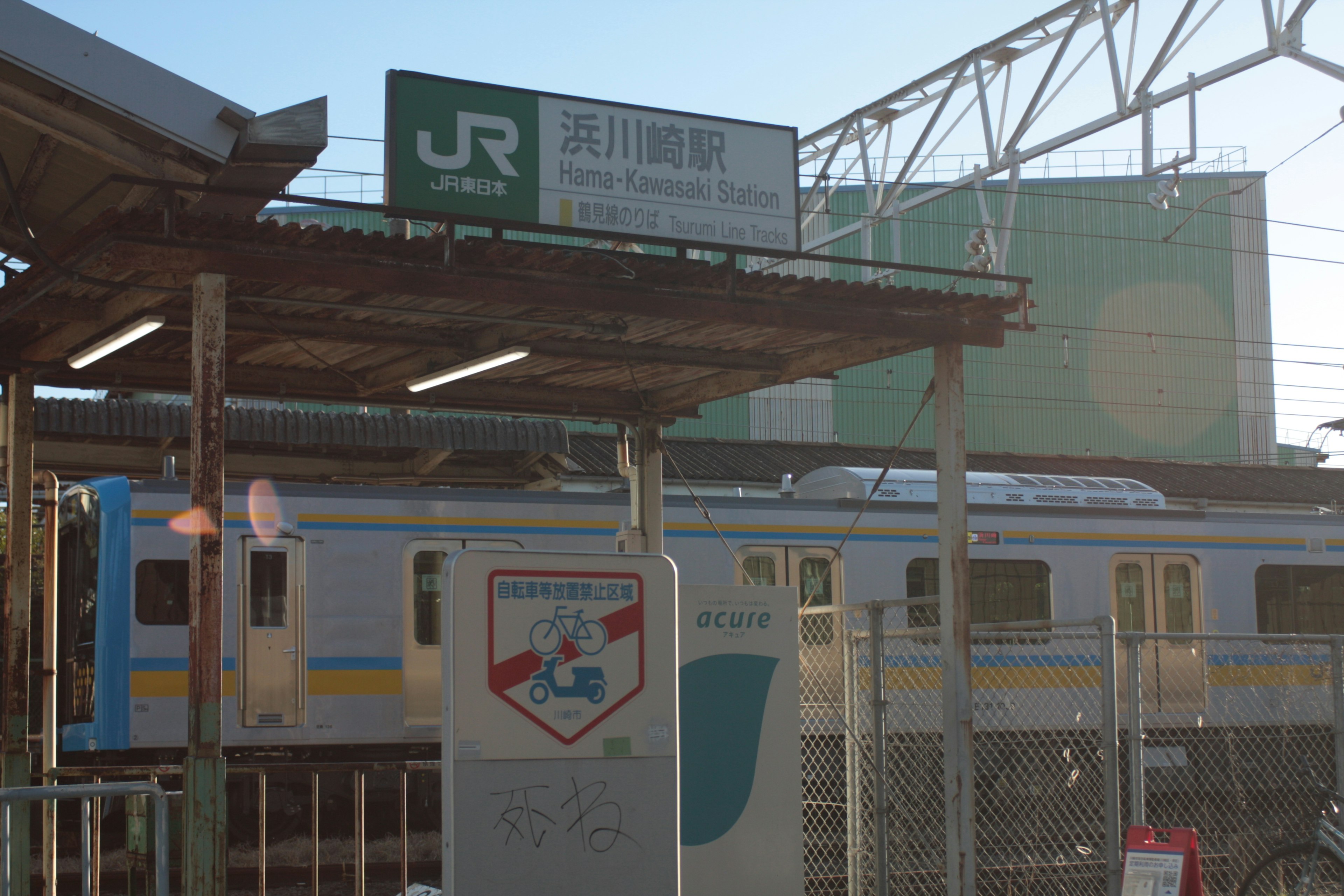 JRの駅の看板と青い電車が見える駅の風景