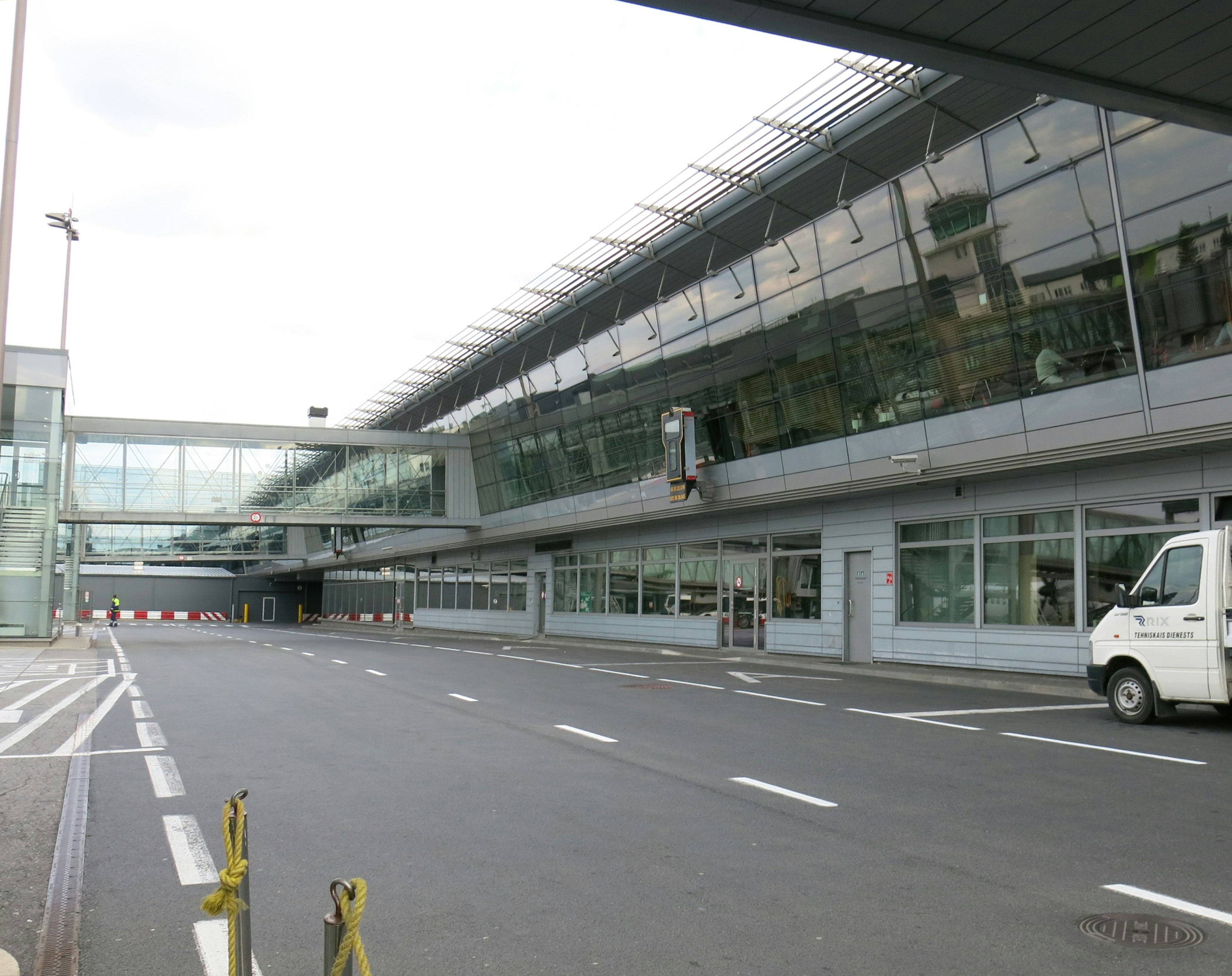 Bangunan bandara modern dengan fasad kaca dan jembatan pejalan kaki